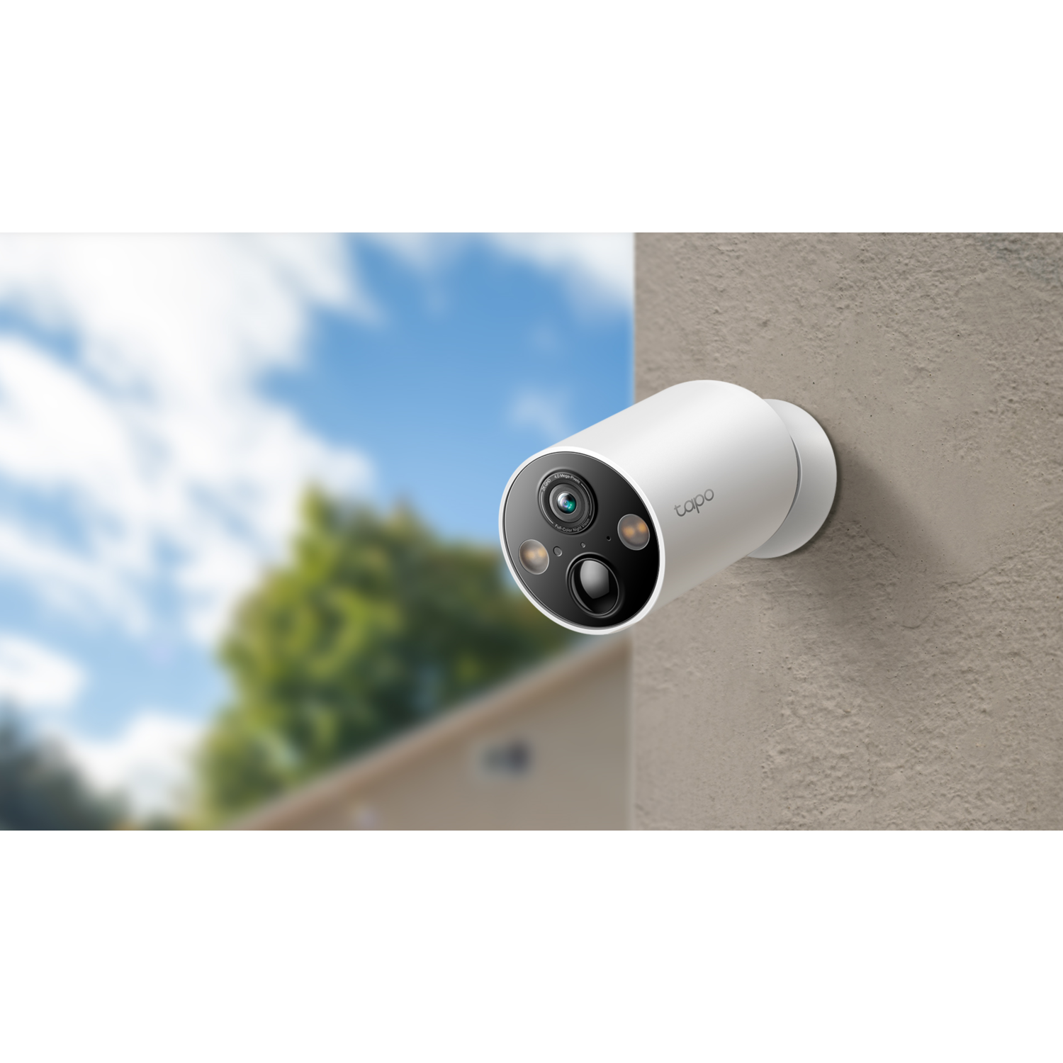 A white security camera mounted on a wall, with a blurred background of trees and sky.