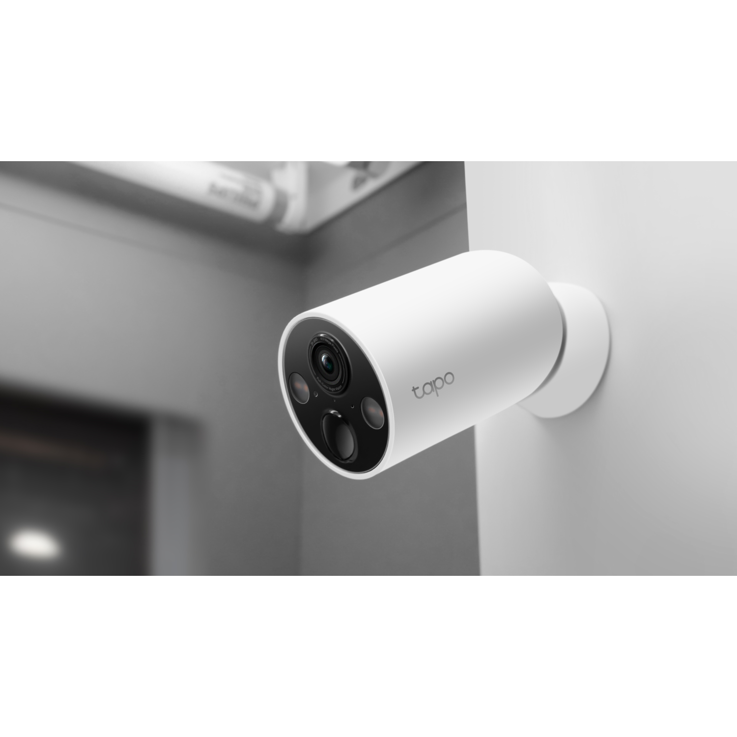 A white Tapo security camera mounted on a white wall, with a black lens.