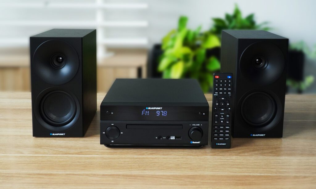 Czarny zestaw stereo z dwoma głośnikami, jednostką centralną z ekranem i pilotem.