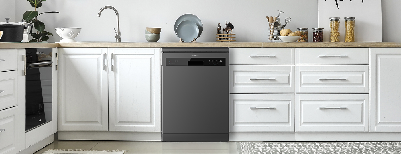 Cocina con gabinetes blancos, un lavavajillas gris y una encimera de madera, con platos y tarros.