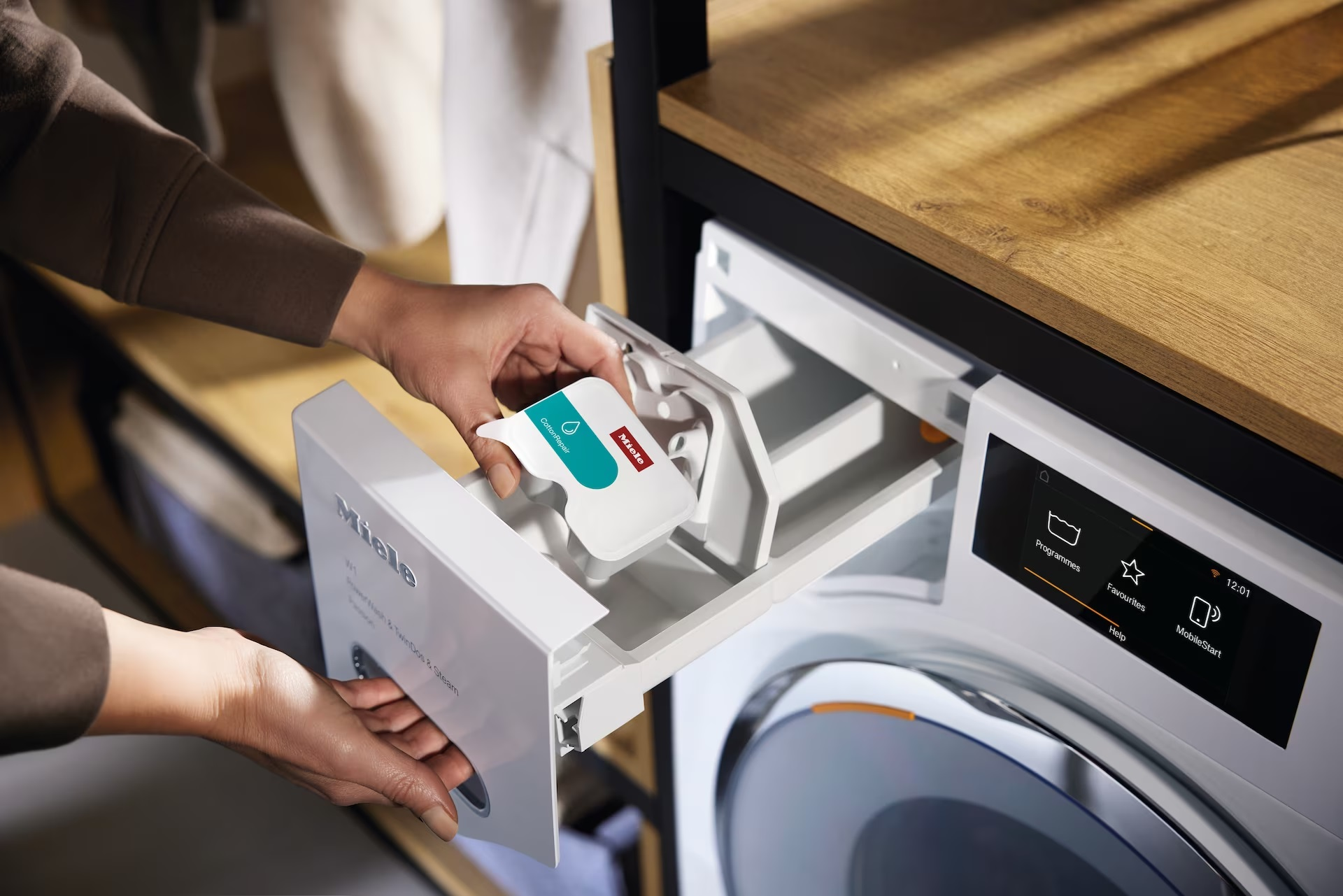 Osoba napełniająca komorę detergentu pralki kapsułką z detergentem.