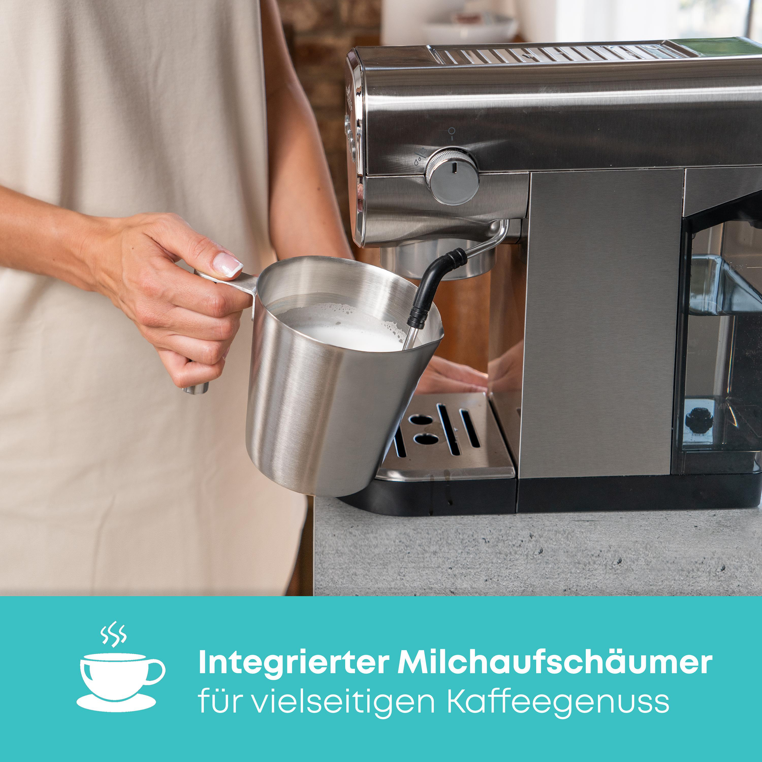 Eine Person bereitet Milchschaum mit einer Espressomaschine zu. Edelstahl-Milchkännchen sichtbar.