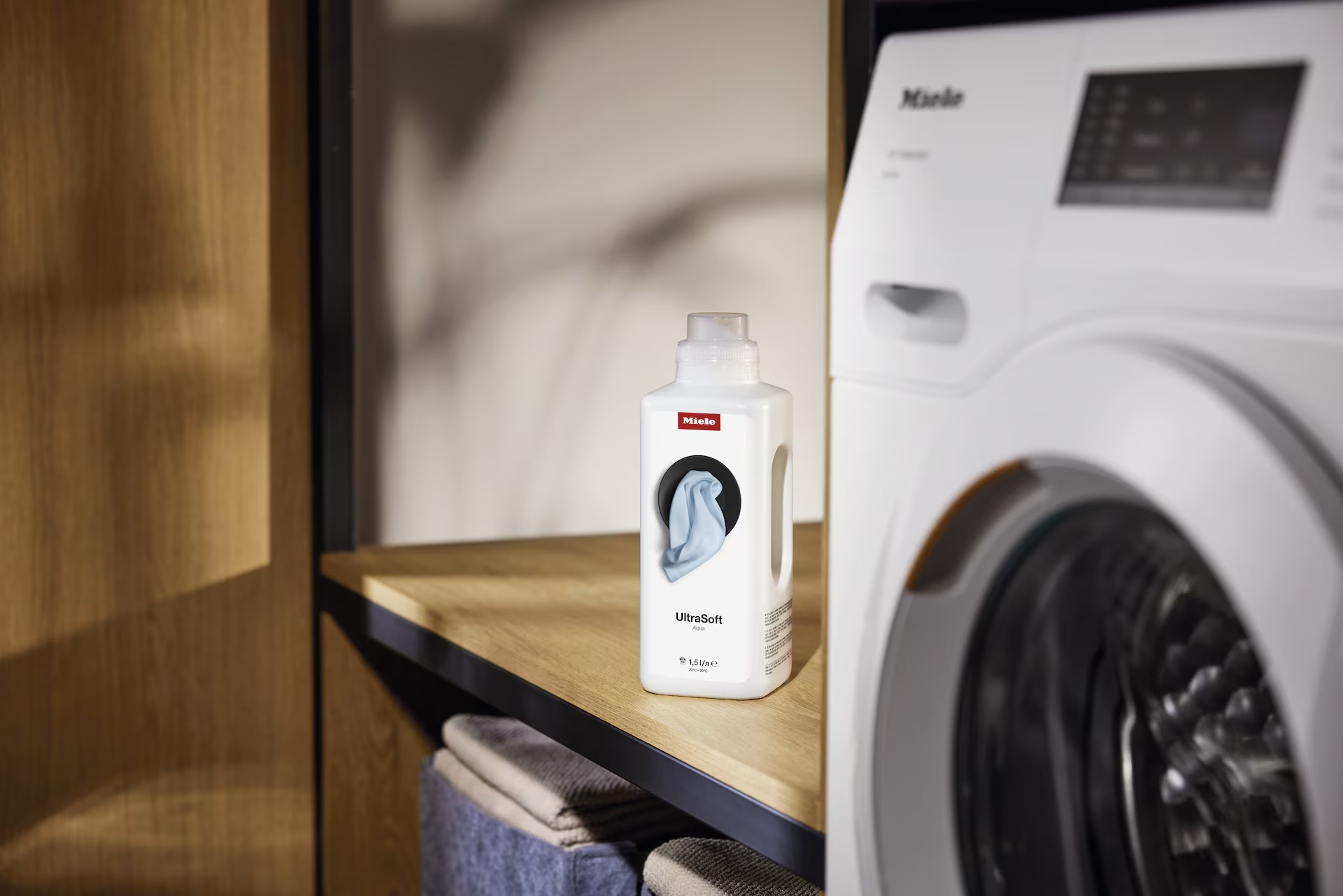 Płyn Miele UltraSoft na półce obok pralki.