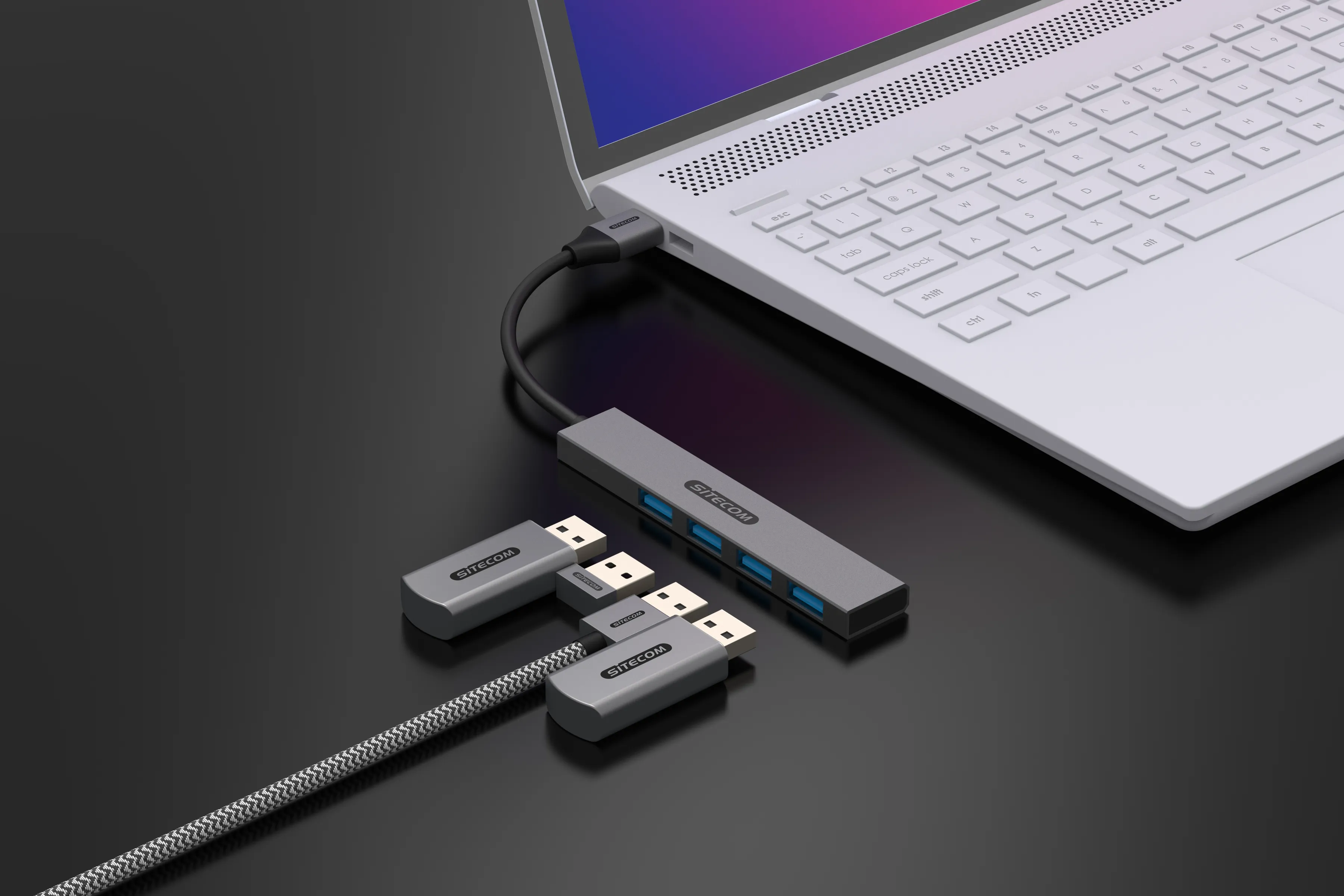 Laptop collegato a un hub con unità USB, su una superficie nera, vista angolata.