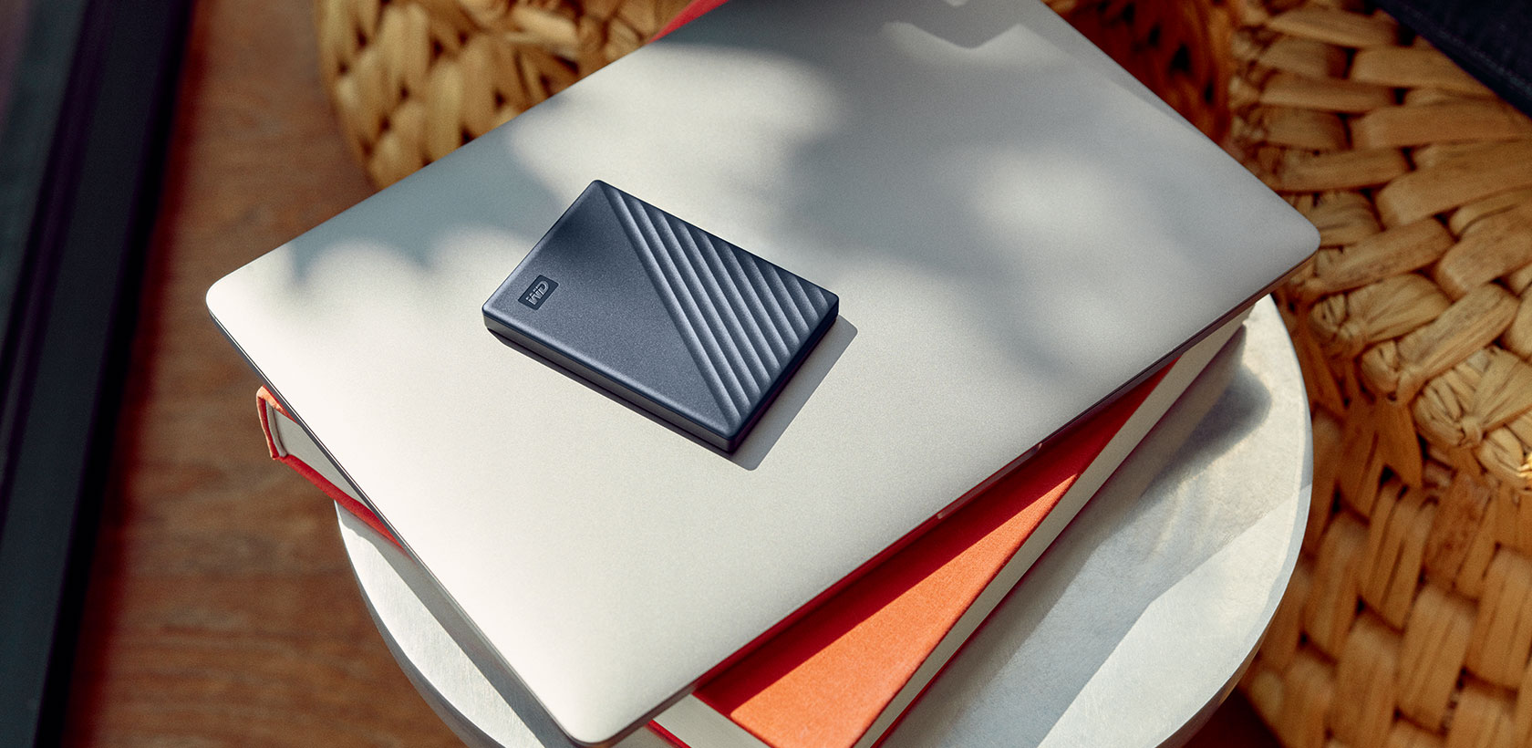Laptop con un disco rigido blu navy sopra, su una pila di libri.