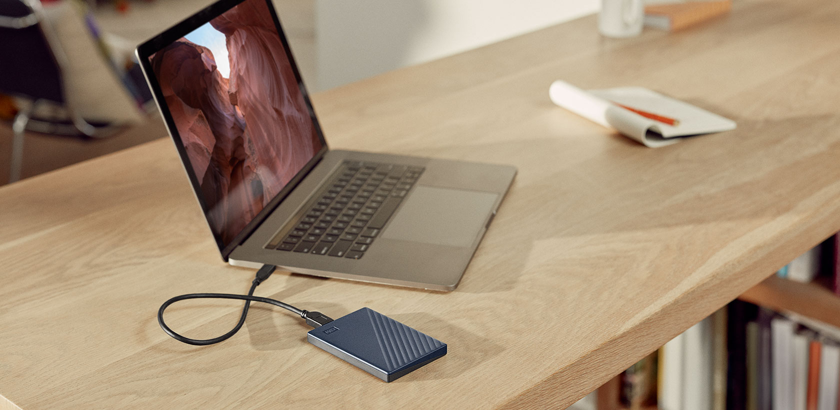 Laptop collegato a un disco rigido portatile su una scrivania di legno.