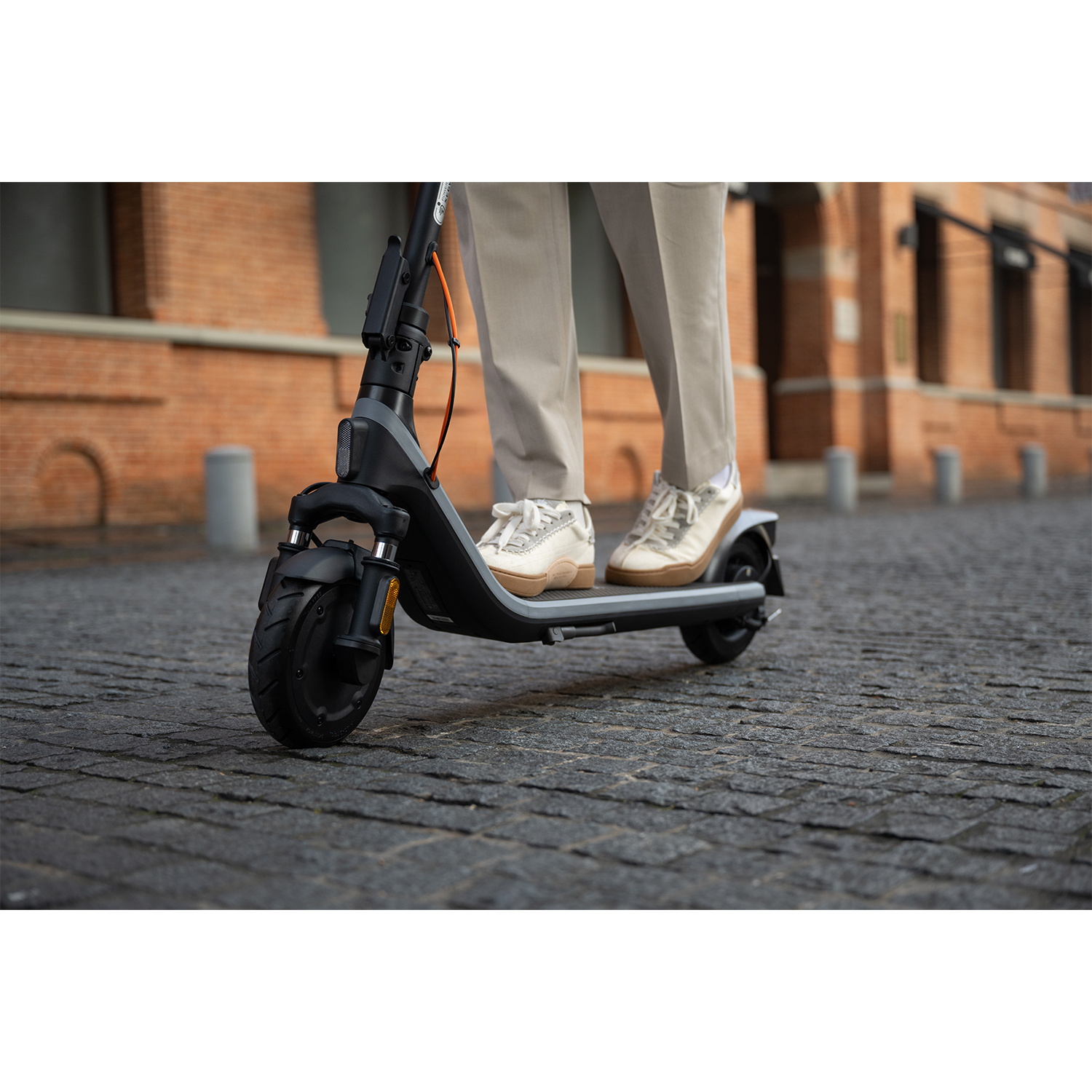 Una persona che guida uno scooter elettrico nero e grigio su una strada acciottolata.