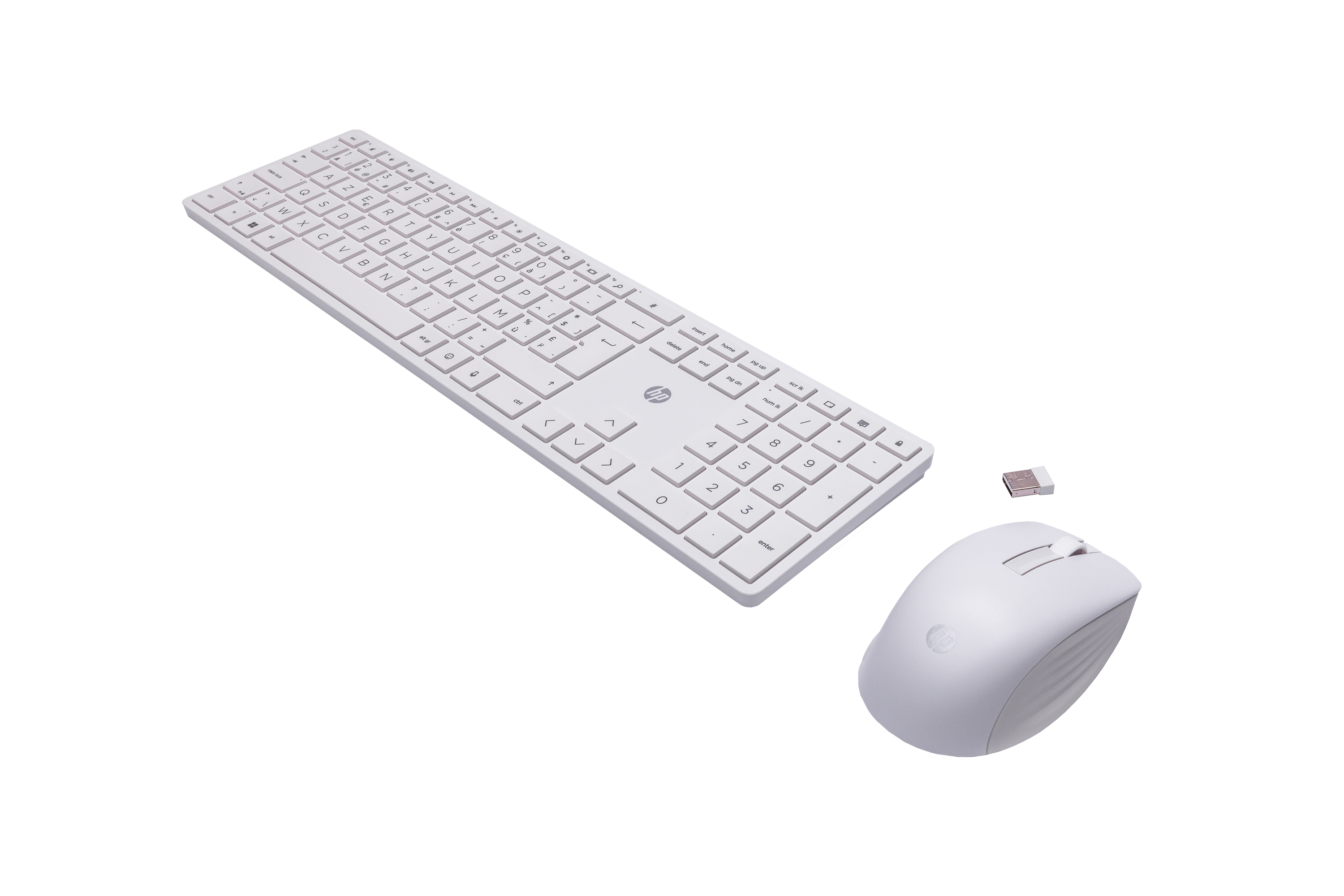 A white wireless keyboard, mouse, and USB receiver on a black surface.