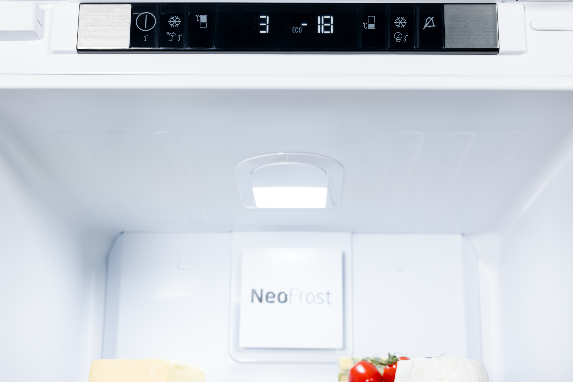 Wnętrze lodówki. Zawiera produkty spożywcze i ma cyfrowy wyświetlacz na górze.