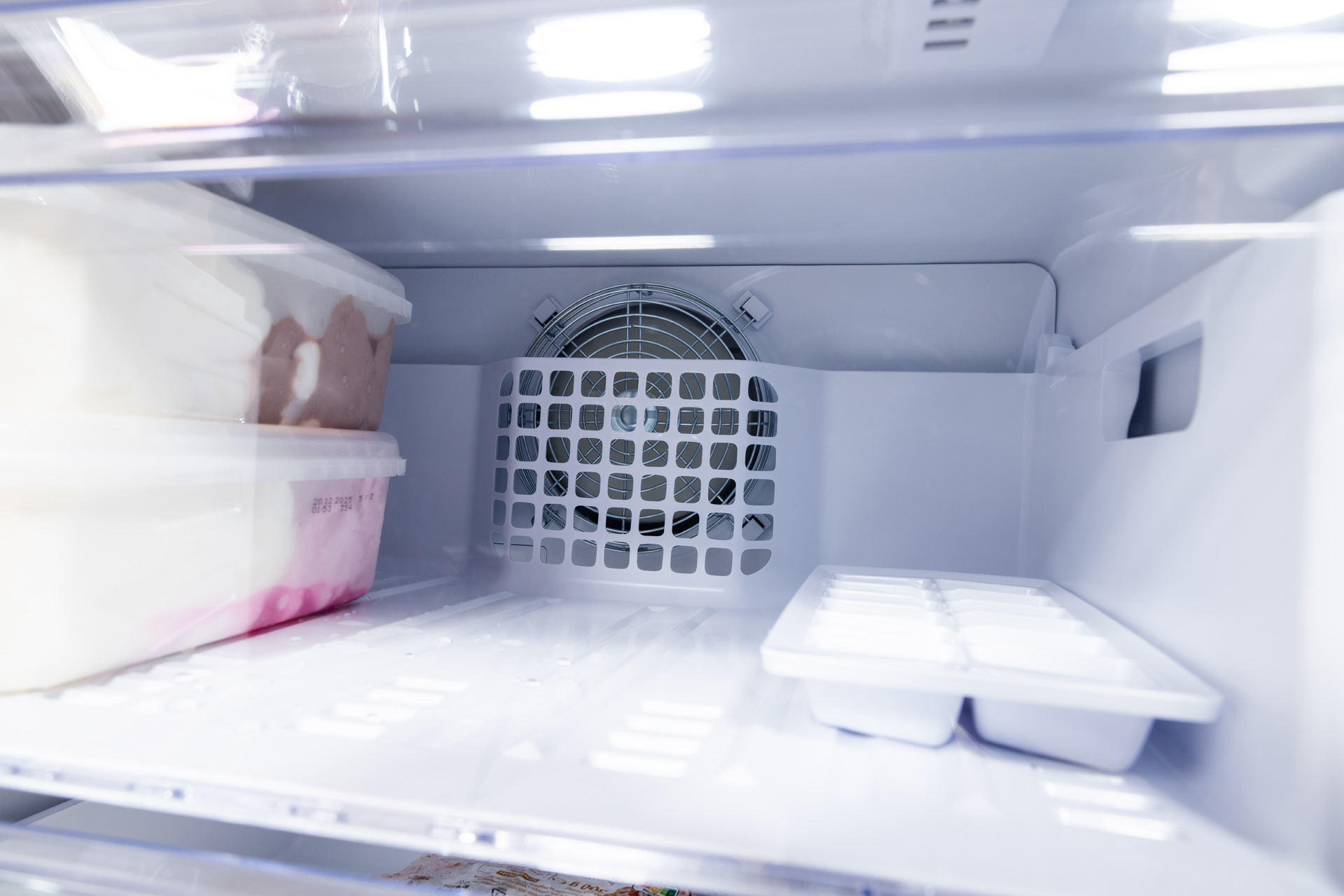 Wnętrze lodówki z lodami i pojemnikami na kostki lodu. Białe wnętrze.