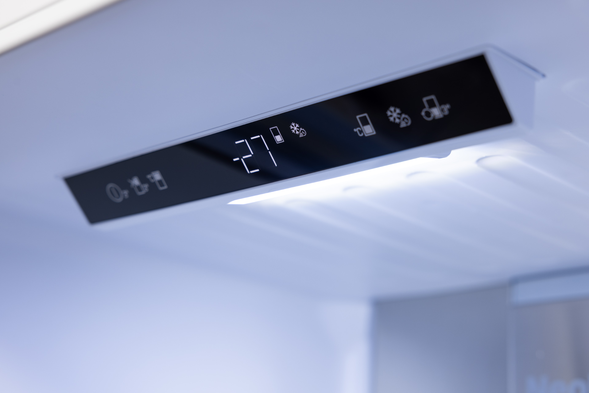 Zbliżenie panelu sterowania lodówki, pokazujące temperaturę 27 i ikony.