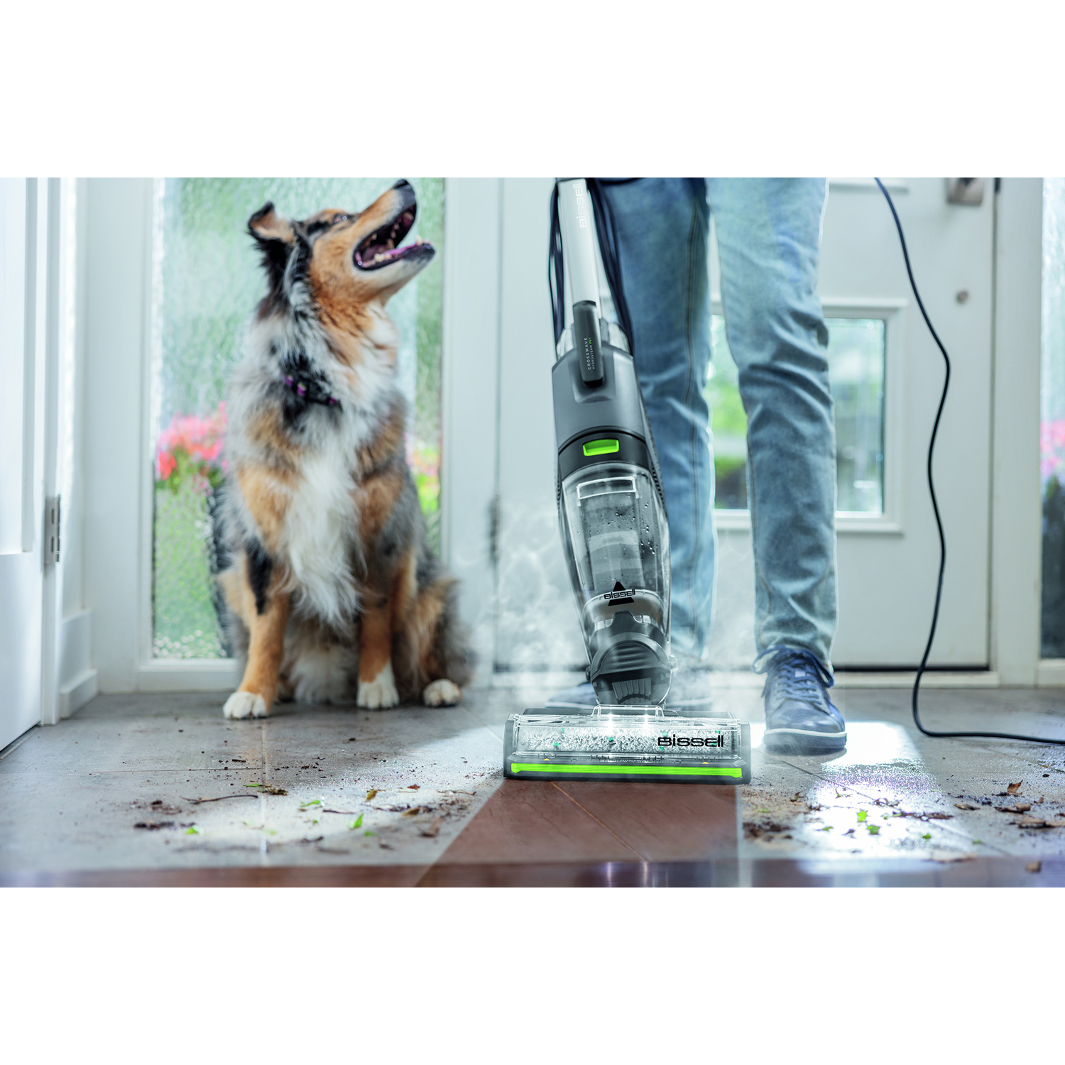Una persona che passa l'aspirapolvere con un cane che guarda.