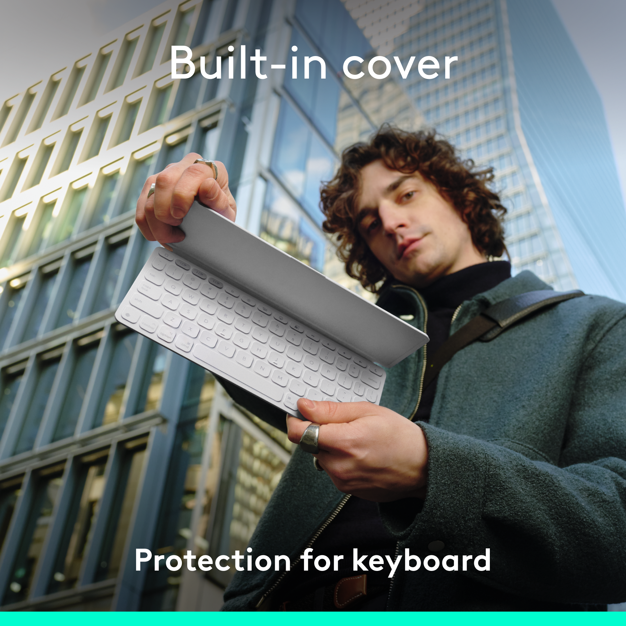 Ein Mann hält eine Tastatur. Die Tastatur ist weiß, und der Mann trägt eine Jacke.