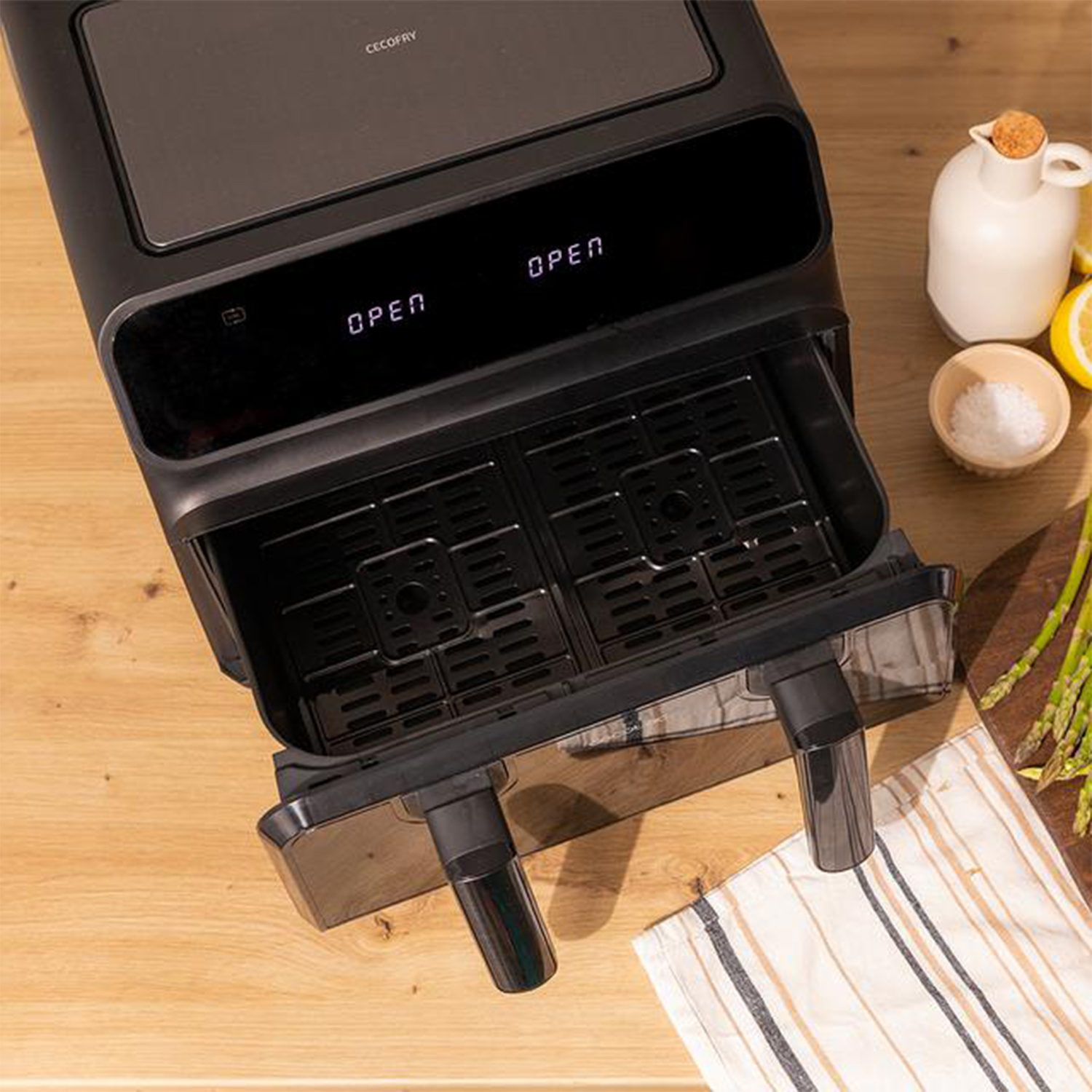 Friggitrice ad aria nera con cestello aperto. Cibo su superficie in legno.