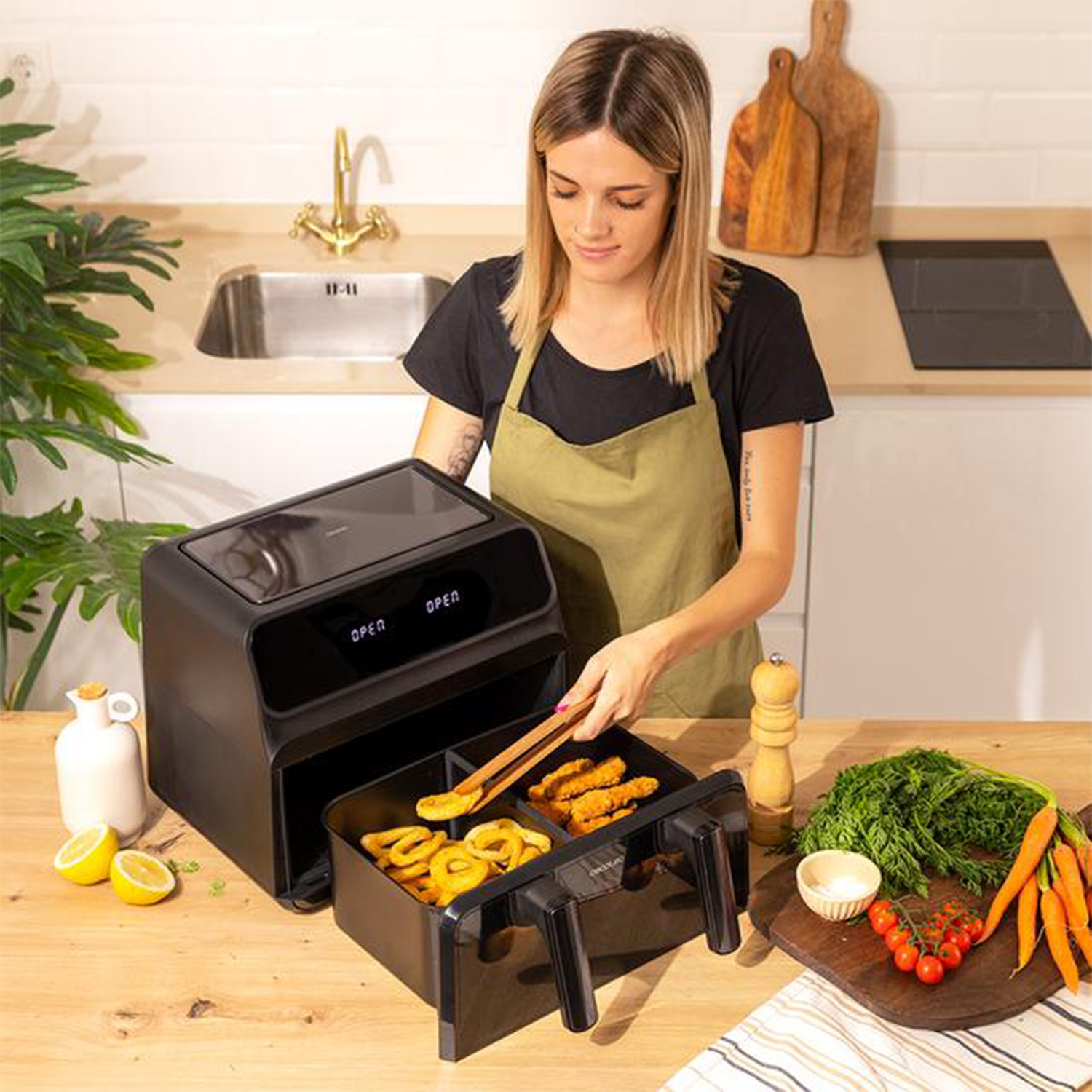 Una donna usa una friggitrice ad aria, posizionando cibo con pinze, con ingredienti e cucina sullo sfondo.