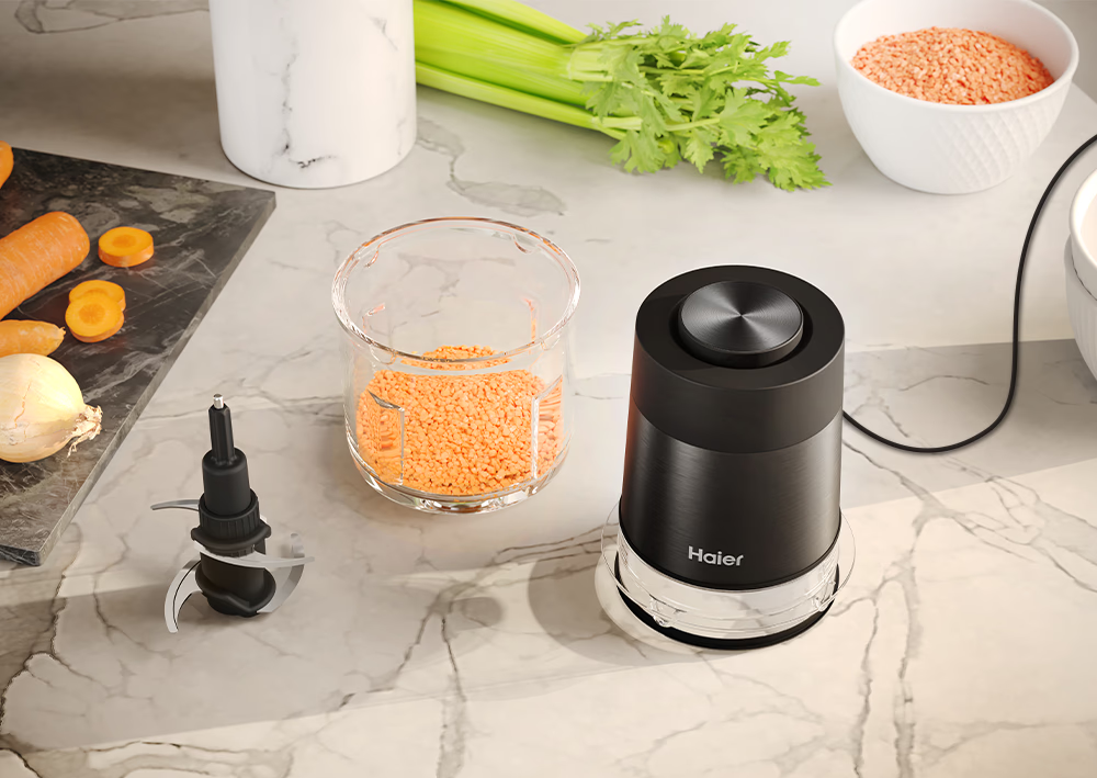 Un robot da cucina con una lama, con lenticchie e altri ingredienti su una superficie di marmo.