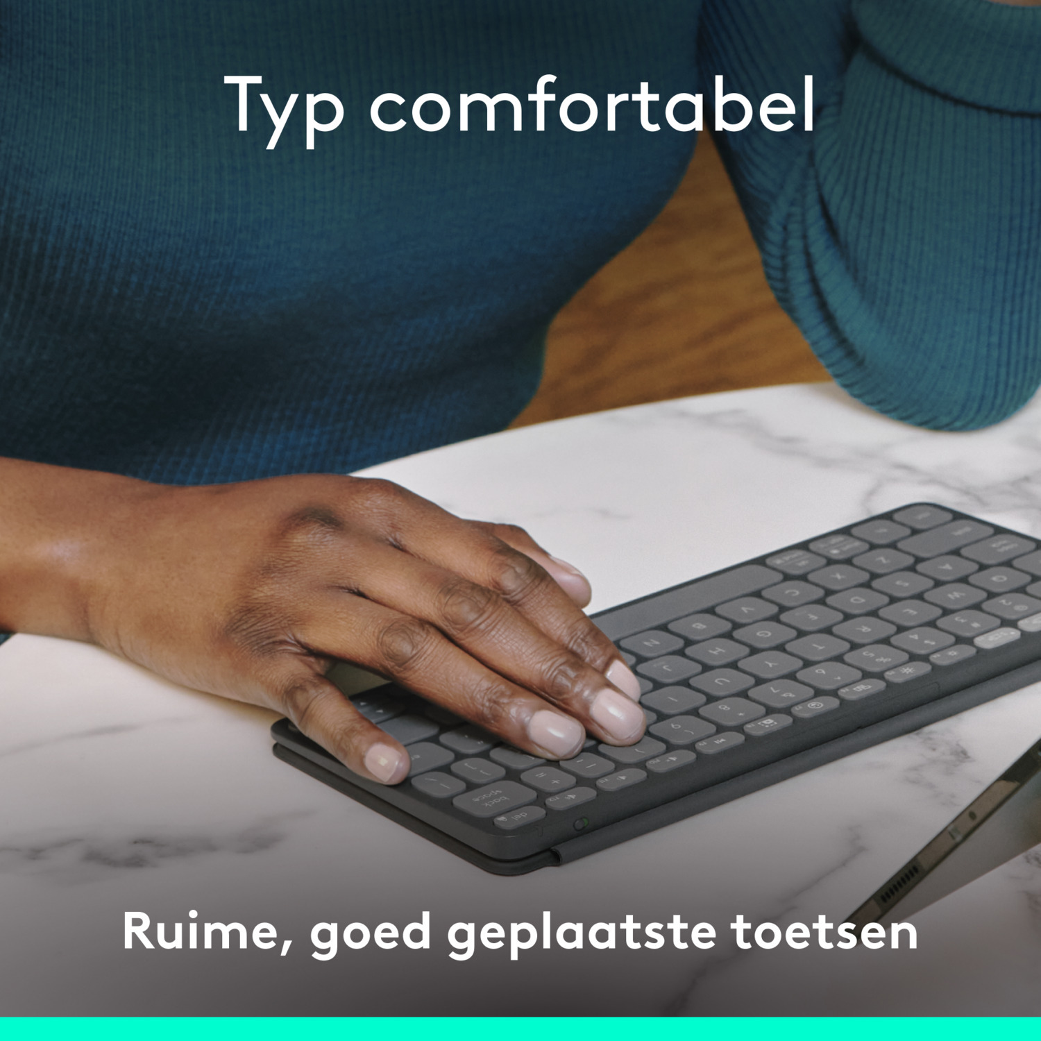 Hands typing on a dark gray keyboard on a marble surface.