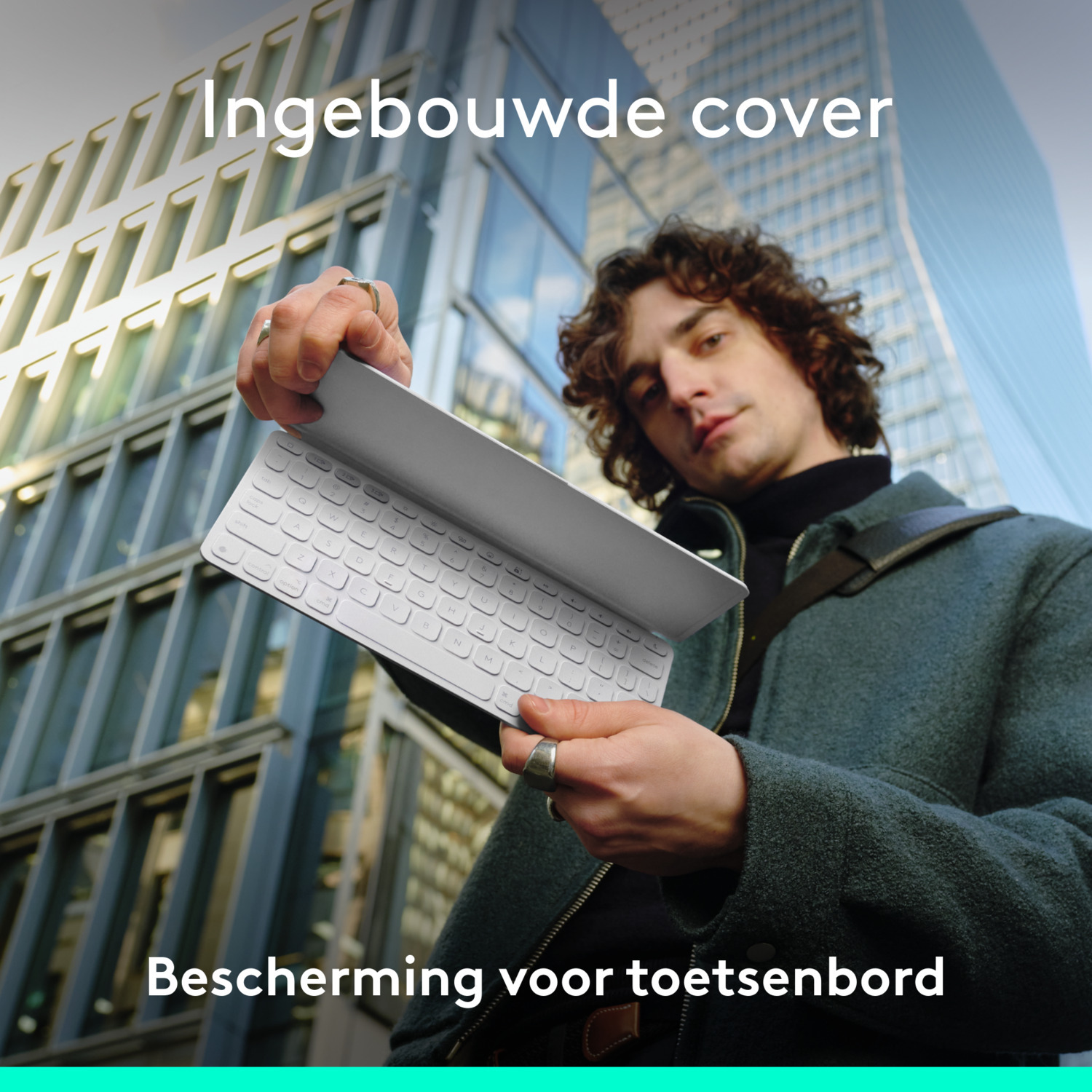 Man holding a keyboard cover in front of a building. The keyboard cover is white.