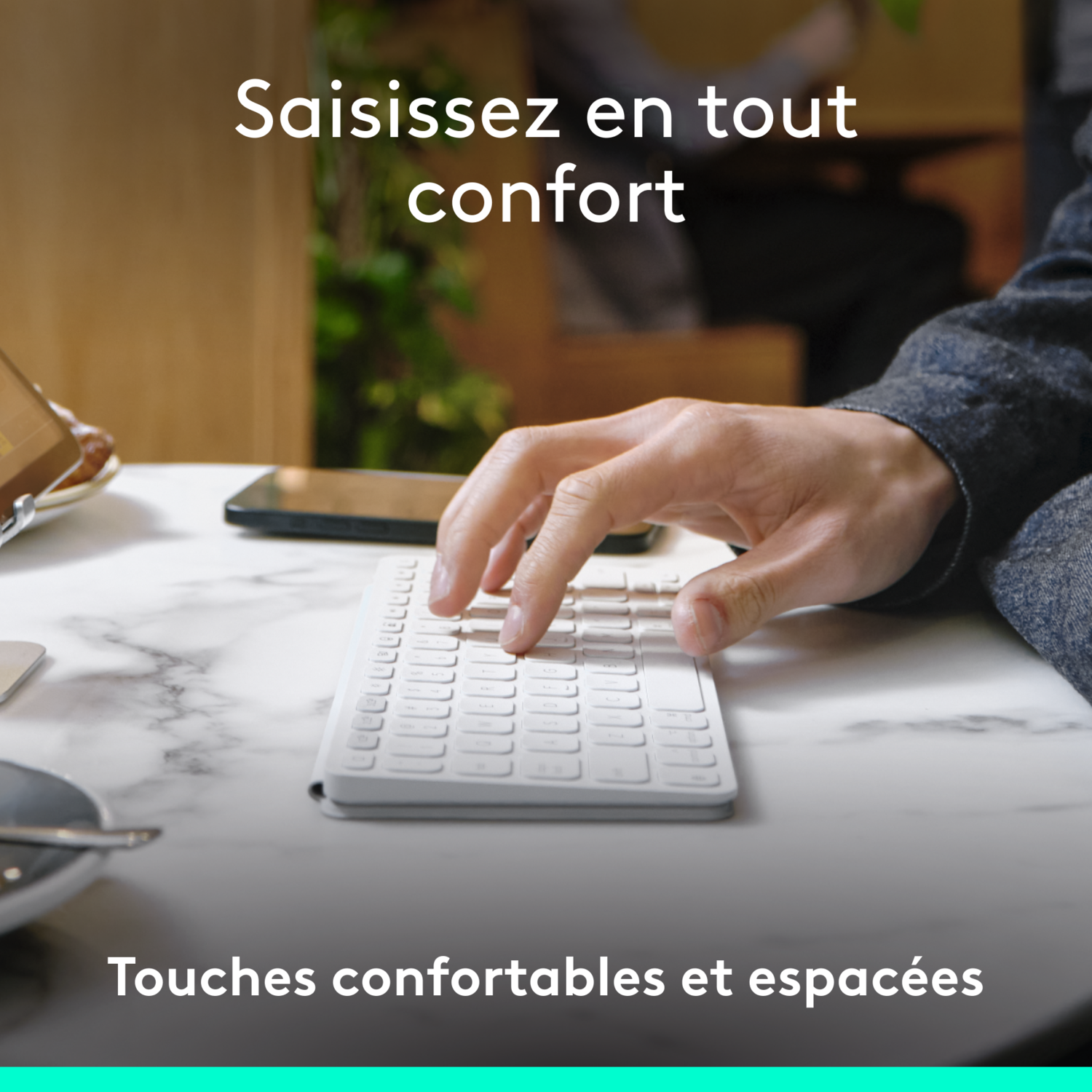 La main d'une personne tape sur un clavier blanc. Le texte dit 'Saisissez en tout confort'.