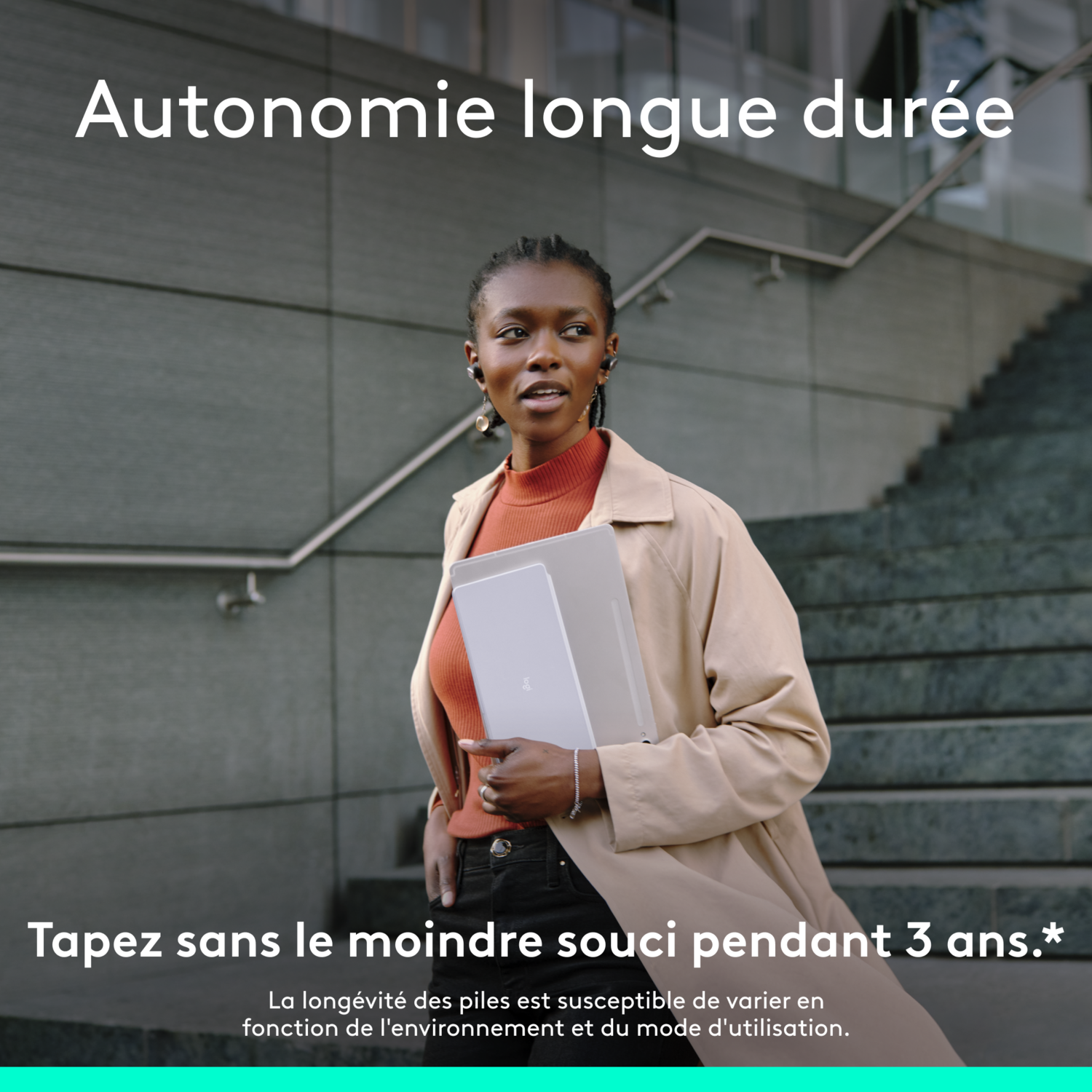 Une femme en manteau beige porte un ordinateur portable argenté. Le texte dit : Longue durée de vie de la batterie et 3 ans.