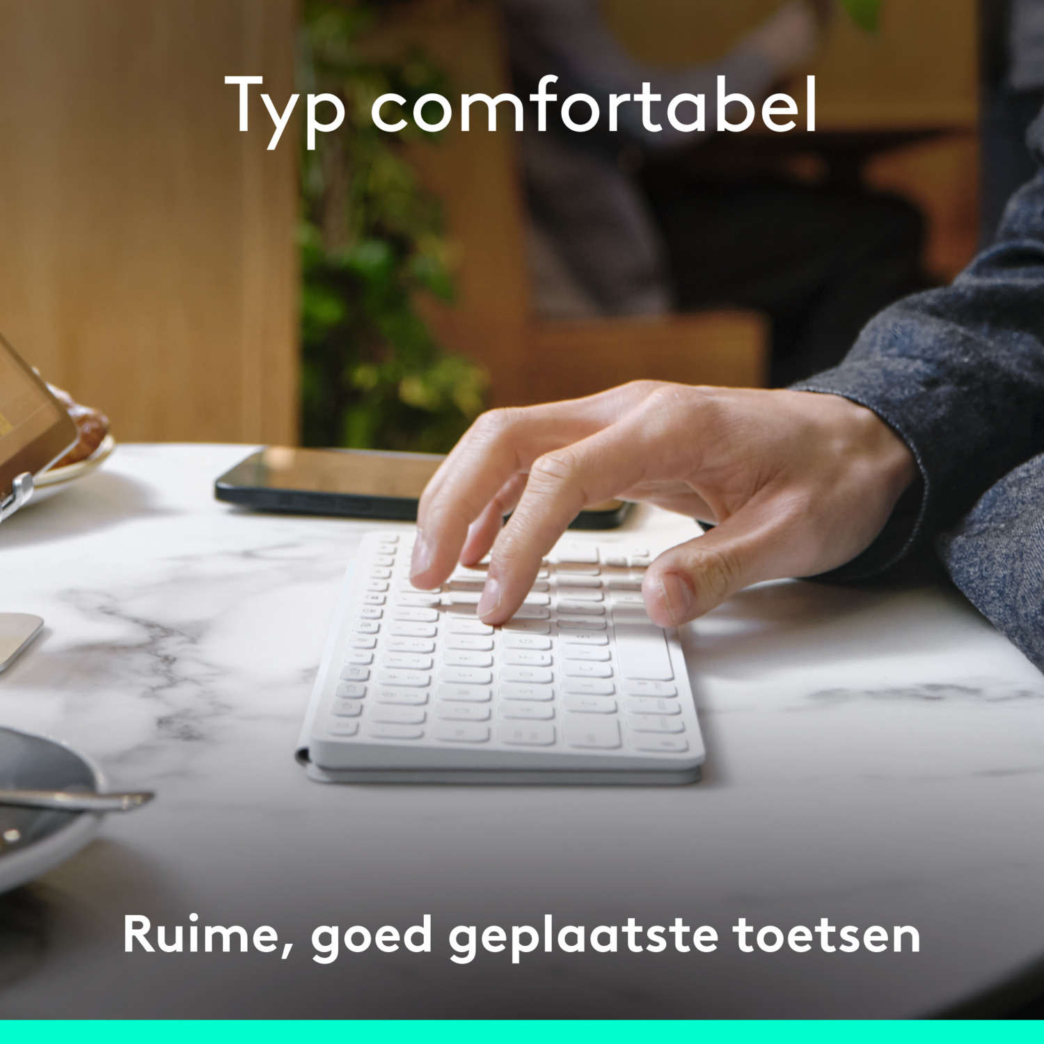 A person typing on a white keyboard on a marble table, close-up shot.