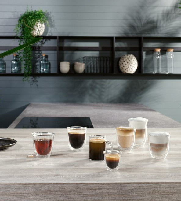 Różne rodzaje kawy w szklanych filiżankach na drewnianym stole.