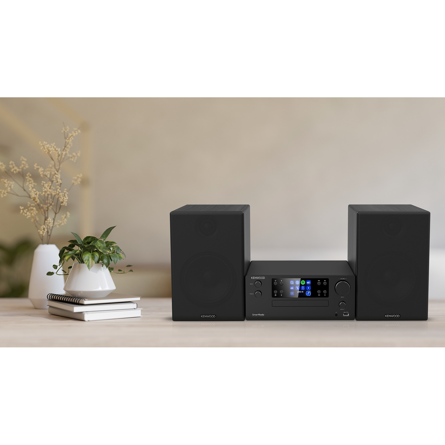 Black stereo system with two speakers and a central unit on a wooden table.