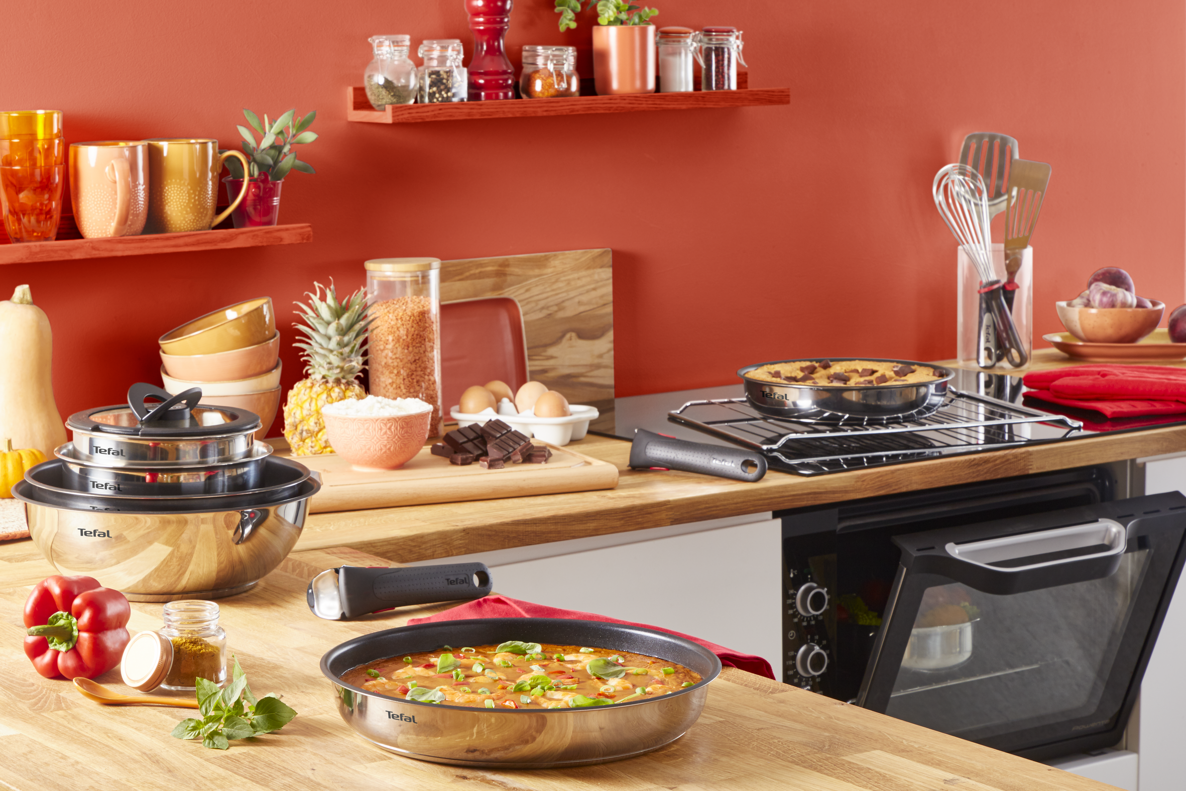 Scena kuchenna z przyborami kuchennymi, produktami spożywczymi i patelnią na drewnianym blacie.