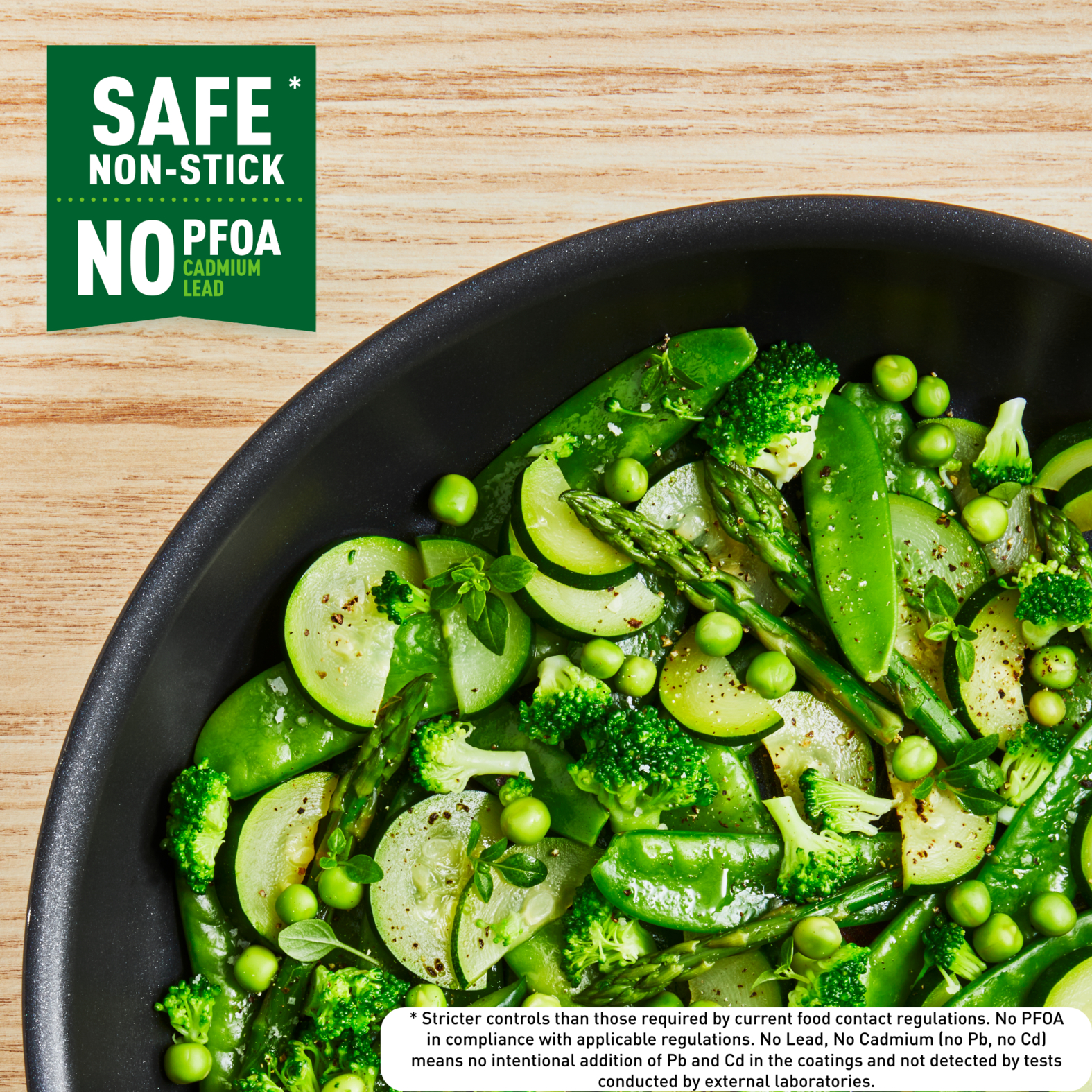 Patelnia z gotowanymi warzywami: groszkiem, brokułami, fasolką szparagową, szparagami. Tekst: 'Safe Non-Stick'.