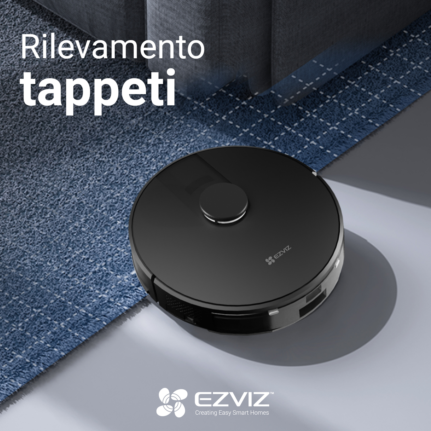 Un aspirapolvere robot nero che pulisce un tappeto blu su un pavimento grigio.