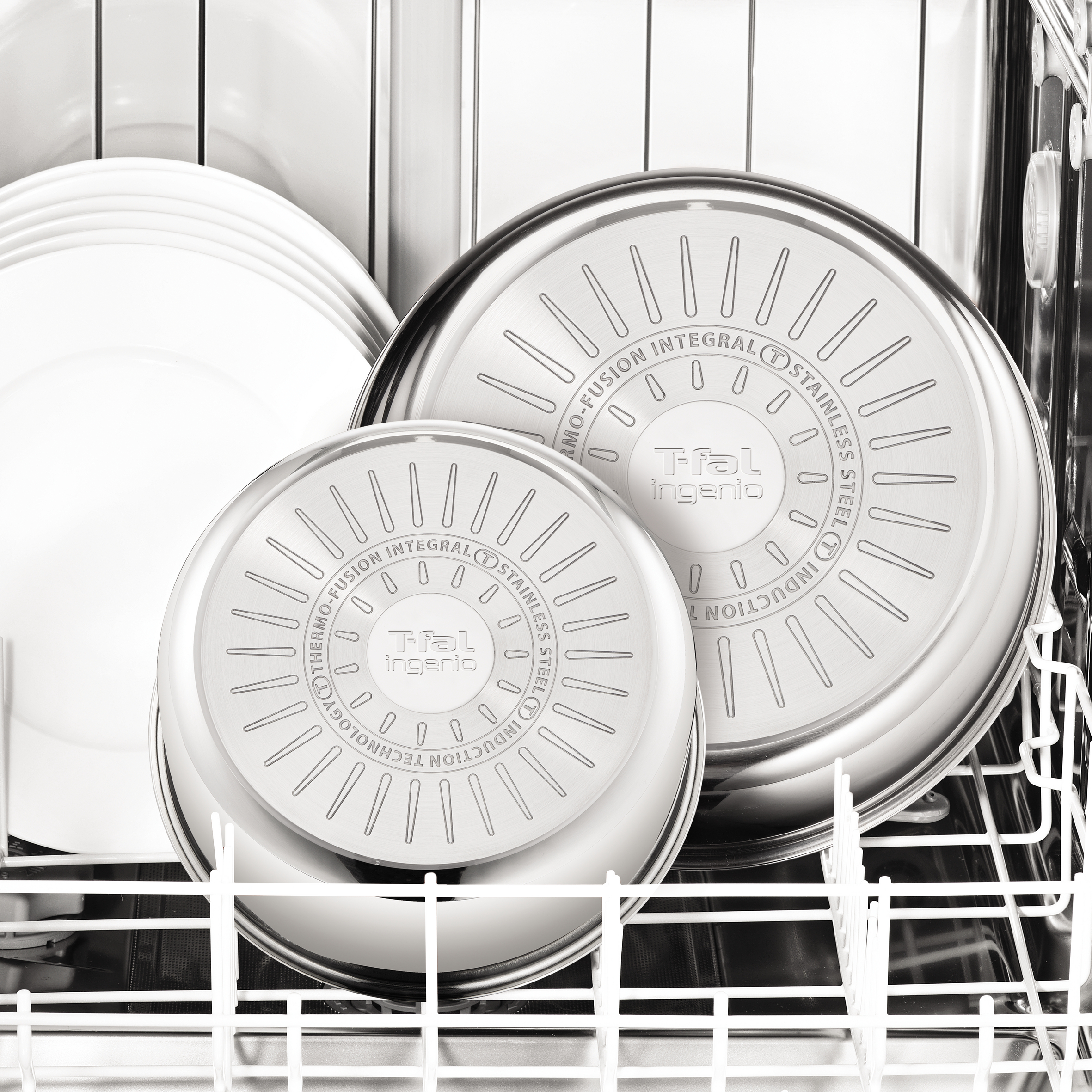 Garnki i patelnie są w zmywarce. Widoczne są dna patelni.