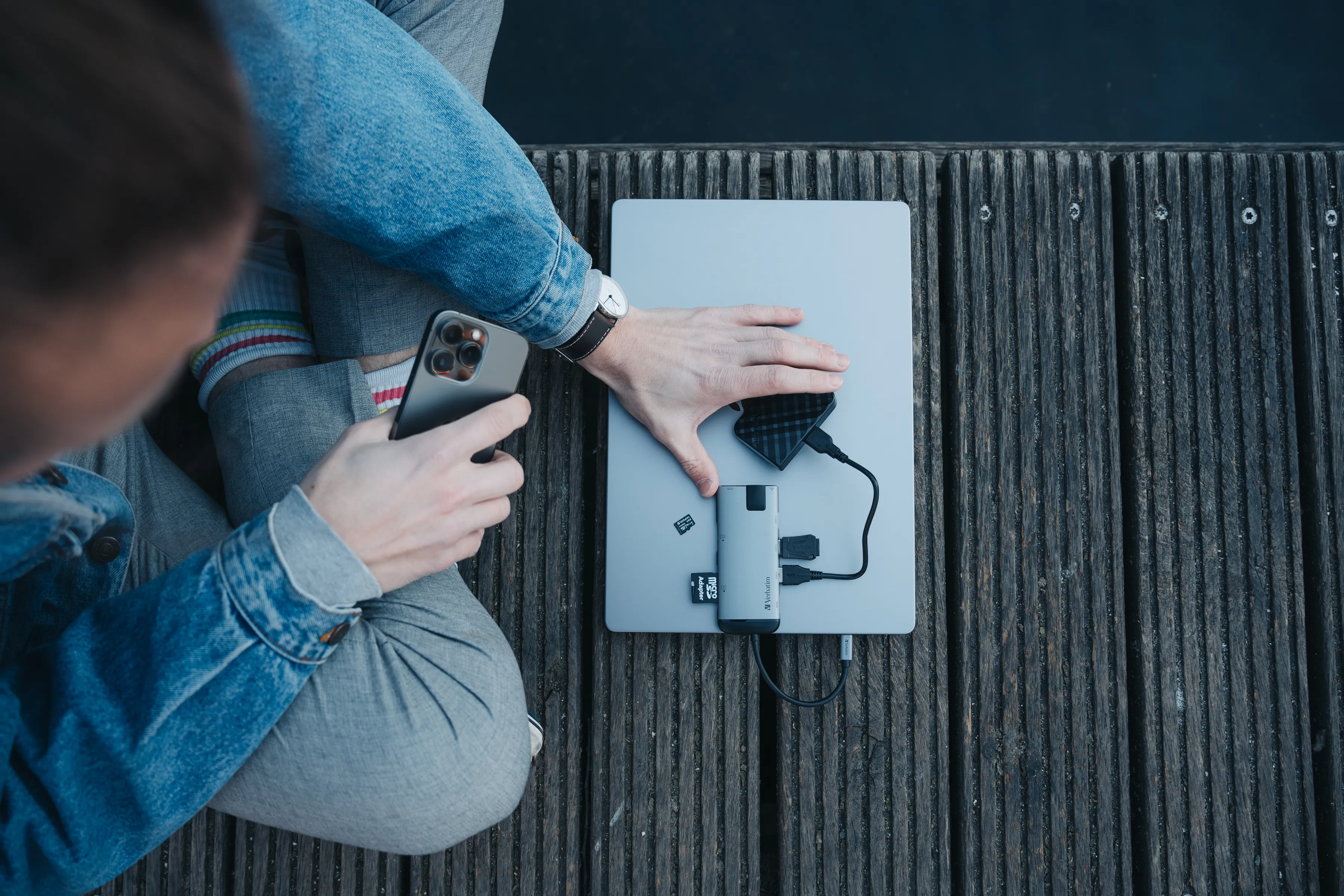 Eine Person, die einen Laptop verwendet, der mit einem Hub verbunden ist. Ein Telefon und andere Geräte.