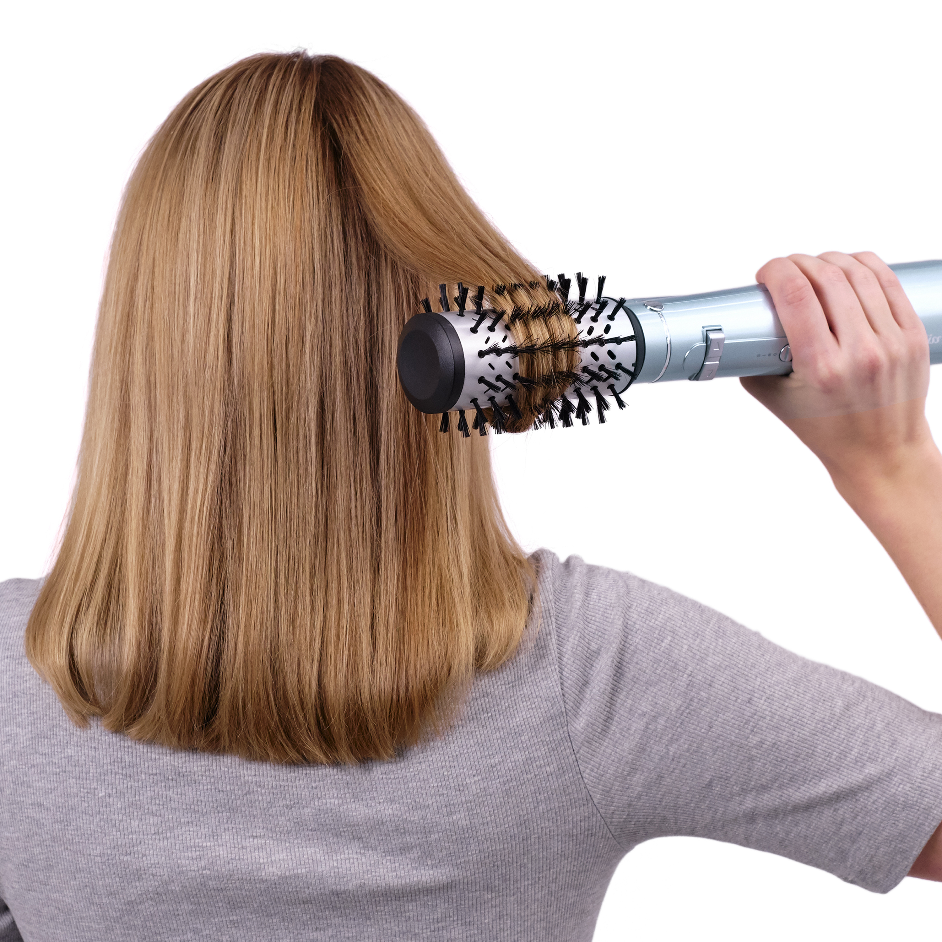 Mujer con cabello rubio usando un cepillo secador de pelo azul.