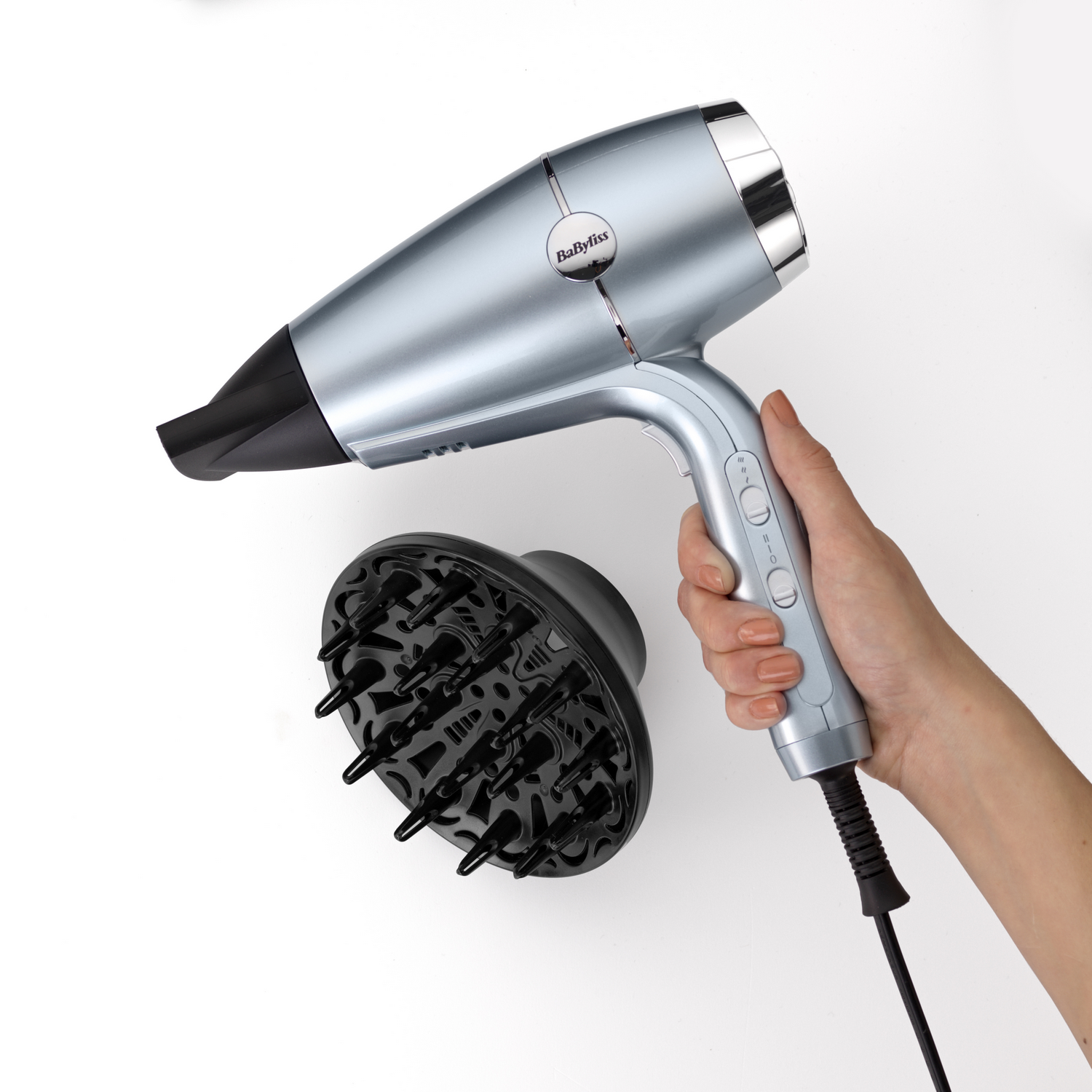 Secador de pelo BaByliss azul claro y un difusor negro sobre una superficie blanca. Mano sostiene.