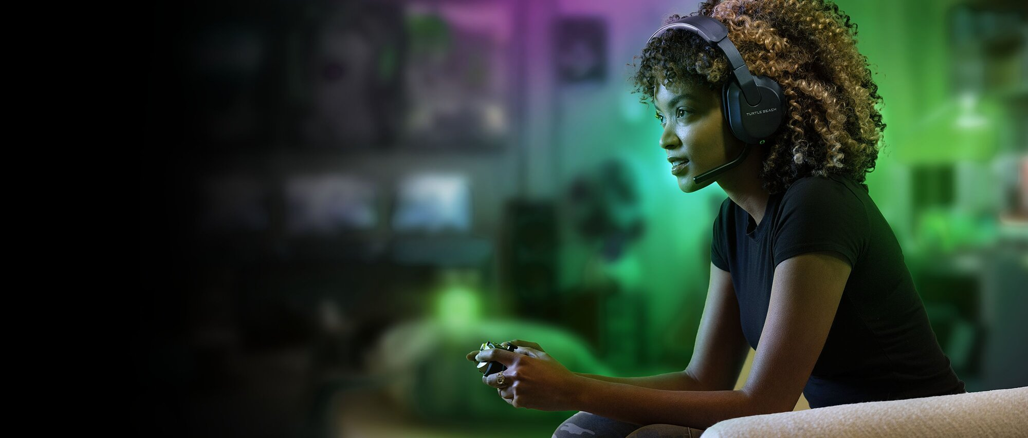 Donna con cuffie gioca ai videogiochi, tiene un controller, in una stanza con luci verdi e viola.
