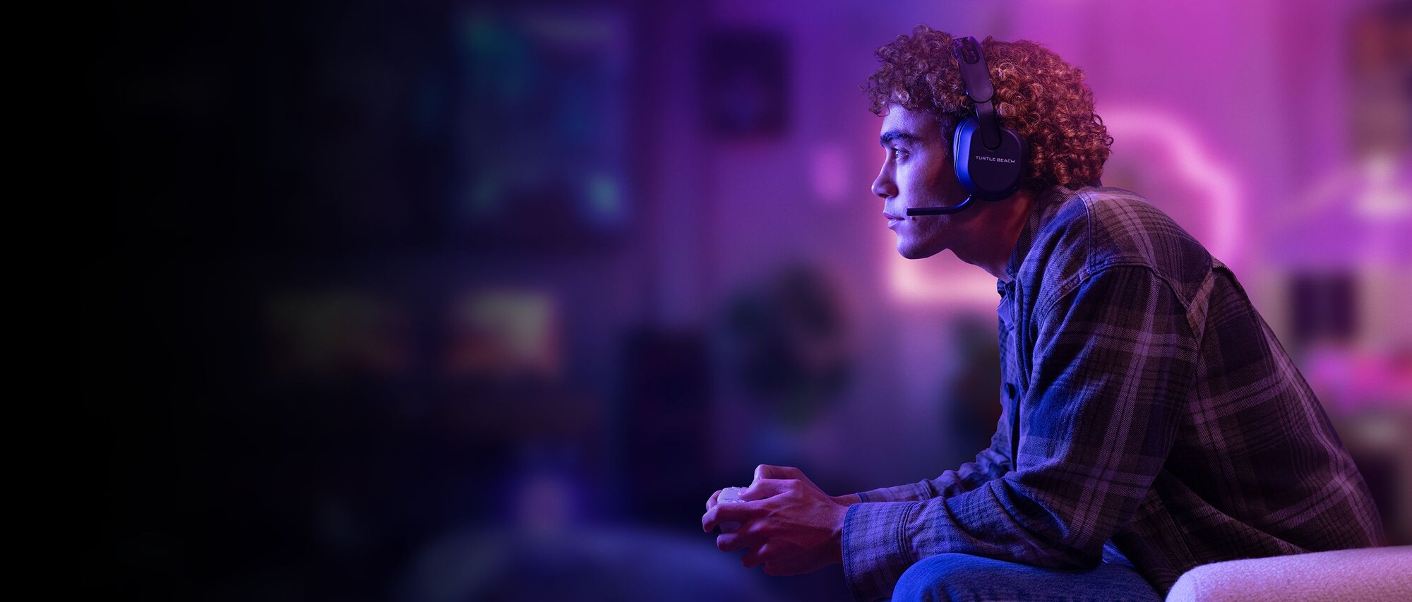 Ein Mann mit Headset spielt ein Spiel, beleuchtet von lila und blauem Licht.
