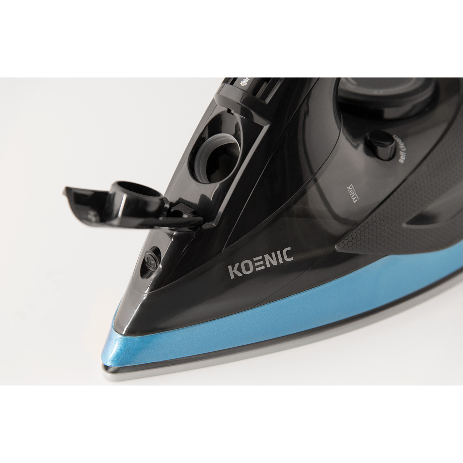 Gros plan sur un fer à repasser noir et bleu. La marque 'KOENIC' est visible.