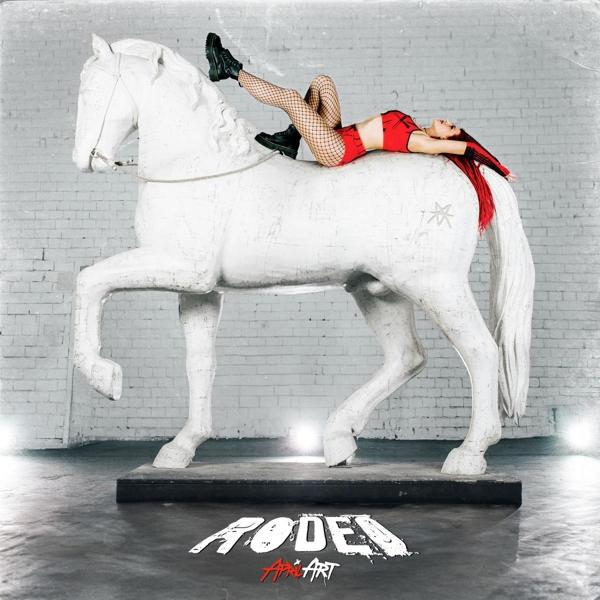 Eine Frau in rotem Outfit liegt auf einer weißen Pferdestatue. Weißer Backsteinmauer Hintergrund. Schwarze Stiefel.
