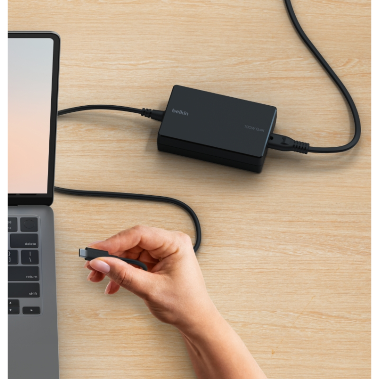 A laptop connected to a black Belkin power adapter and charging cable.