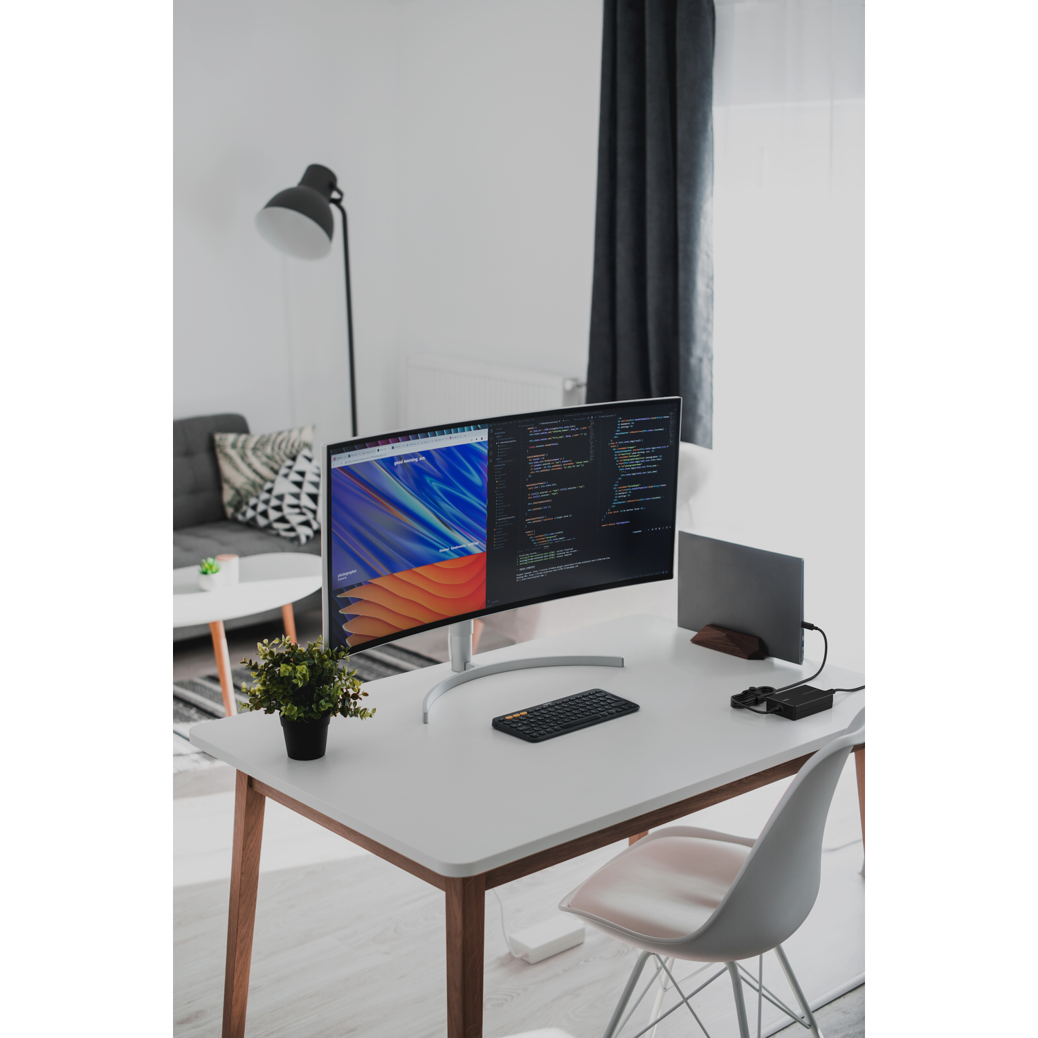 A modern desk setup with a monitor, keyboard, mouse, and plant on a white desk.