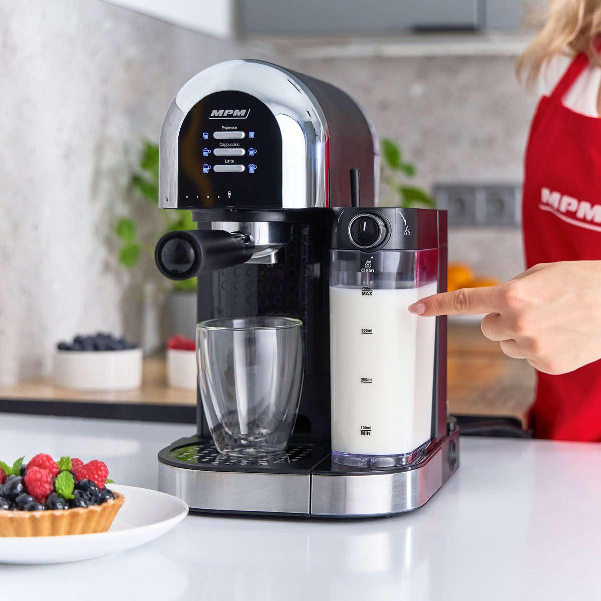 Ekspres do kawy z spieniaczem do mleka. Ręka wskazuje na pojemnik z mlekiem.