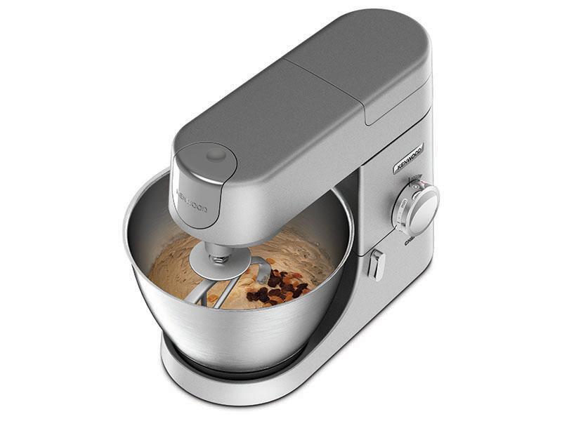 Ein silberner Kenwood Küchenmixer mit einer Rührschüssel mit Teig und Rosinen.