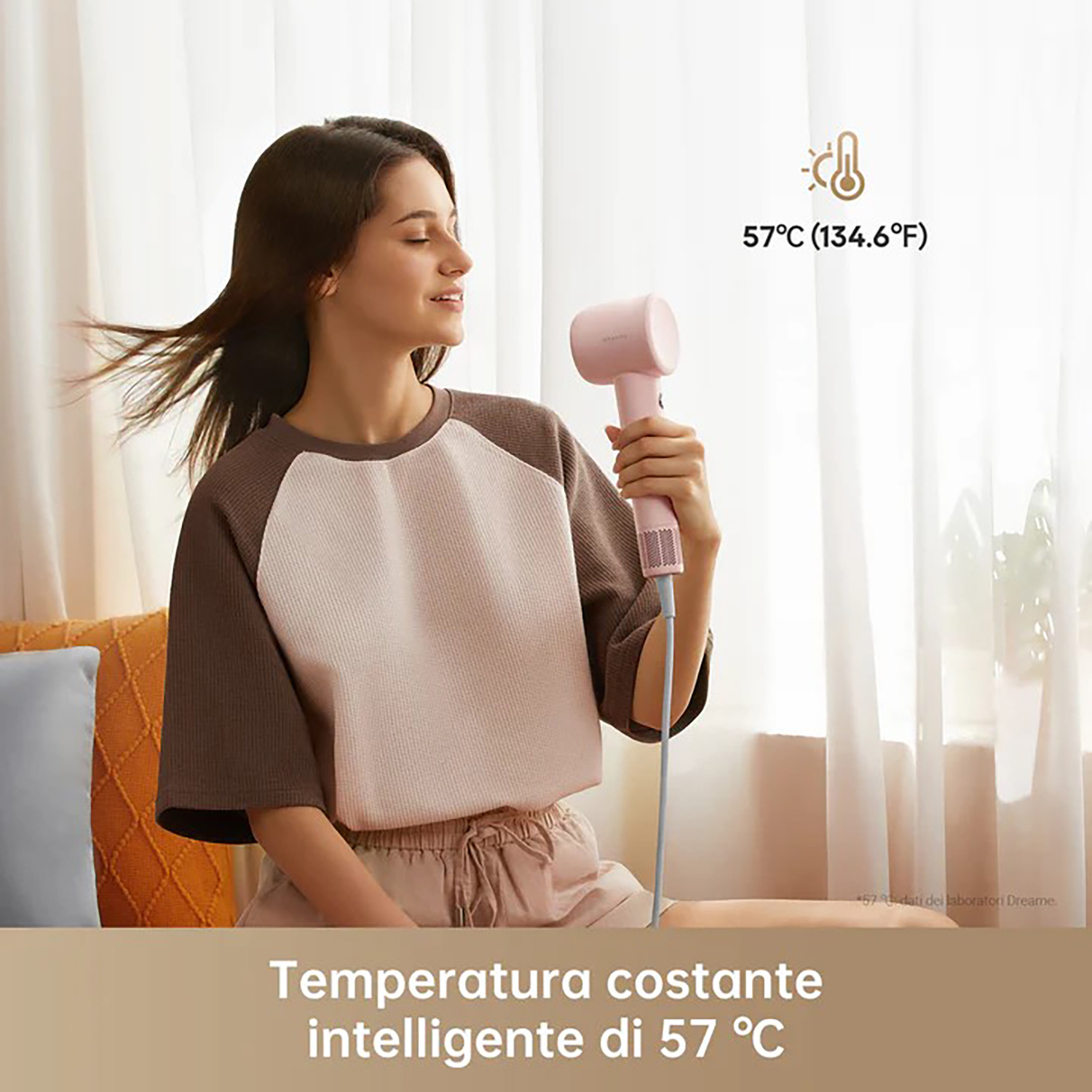 Una donna usa un asciugacapelli rosa, con un indicatore di temperatura che mostra 57°C, in una stanza.