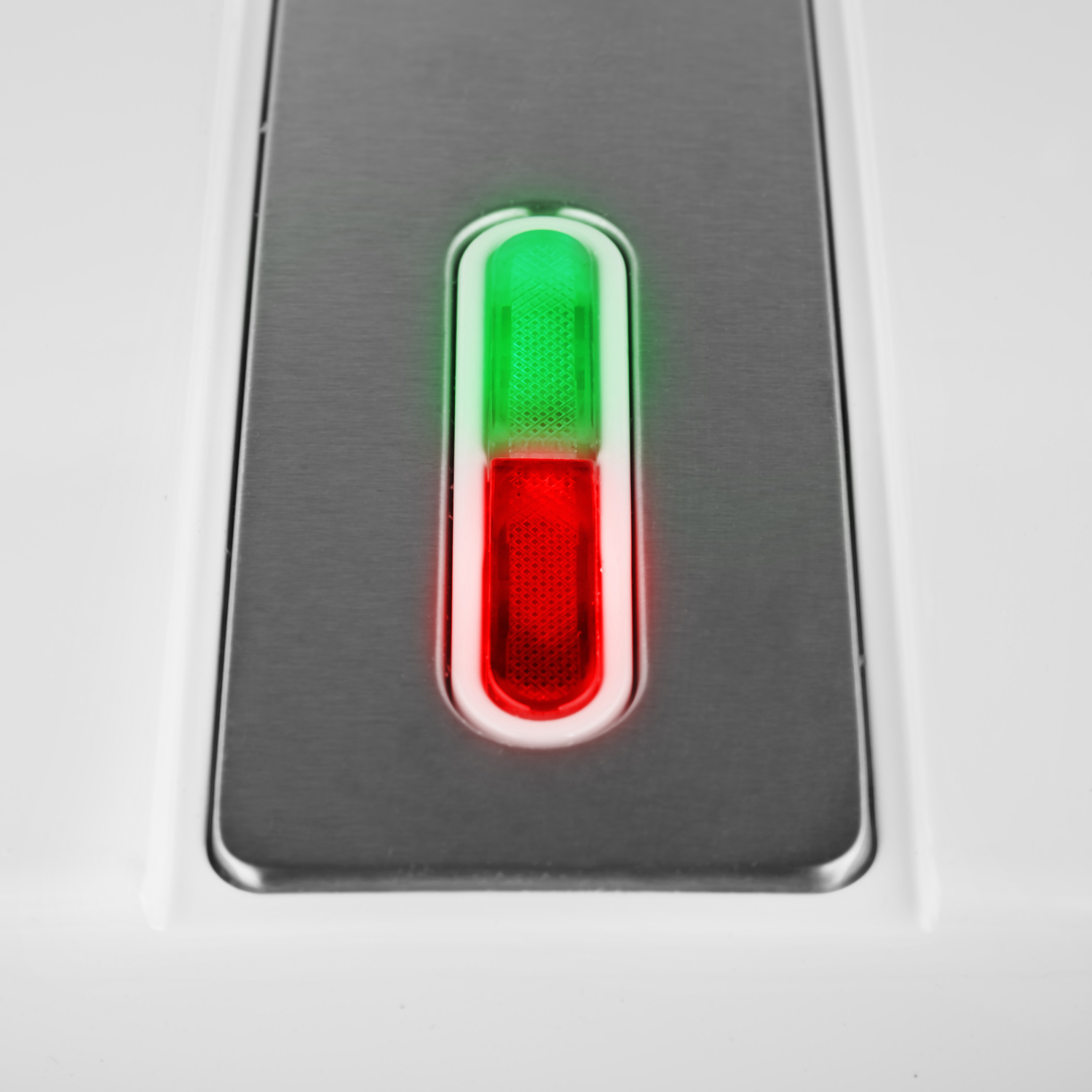 Primer plano de un dispositivo con un indicador de luz verde y roja. Carcasa plateada y blanca.