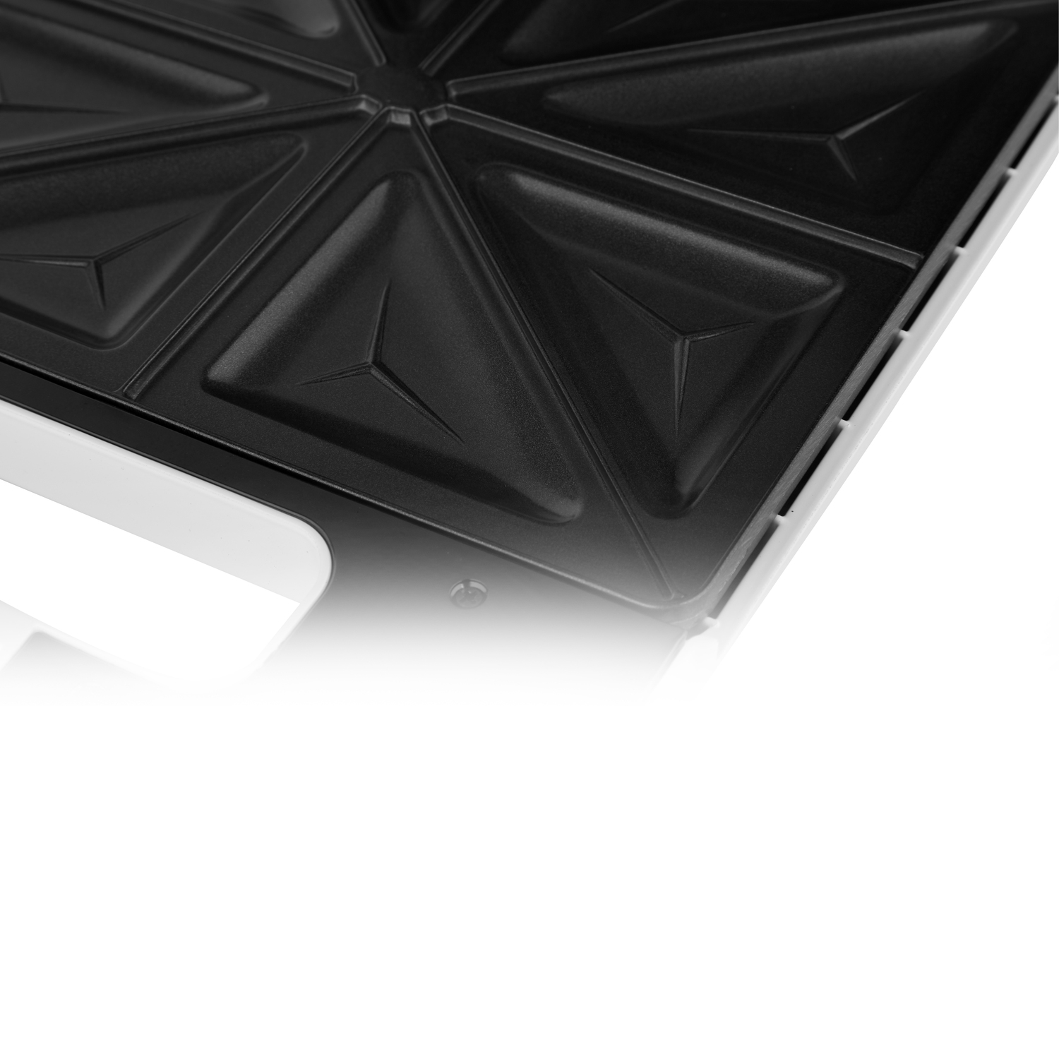 Primer plano de la superficie de cocción de una sandwichera que muestra compartimentos triangulares.