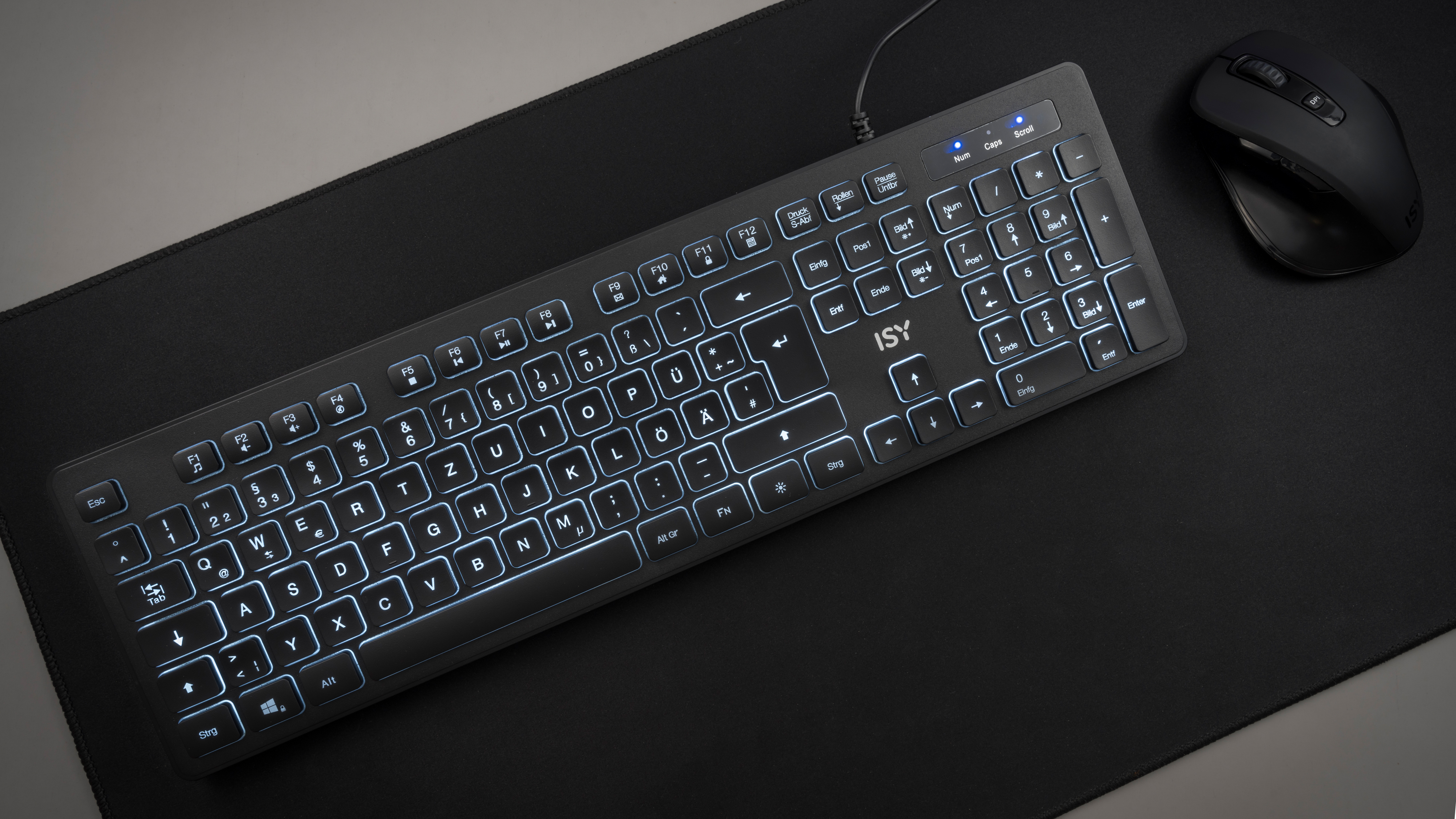 Eine beleuchtete Tastatur und eine Maus auf einem schwarzen Mauspad, Draufsicht.