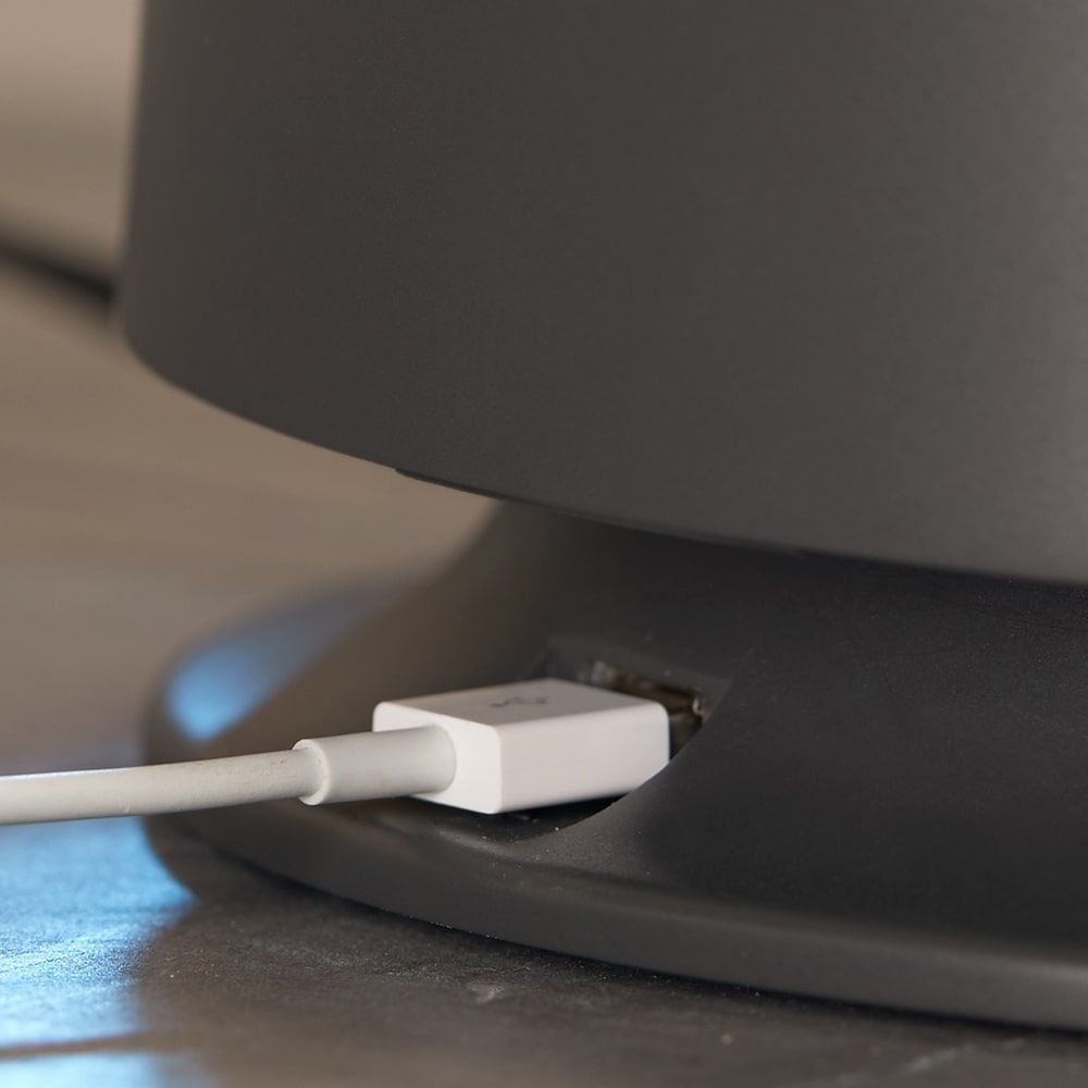 Zbliżenie ciemnoszarego urządzenia z włożonym kablem USB. Kabel ma białe złącze.