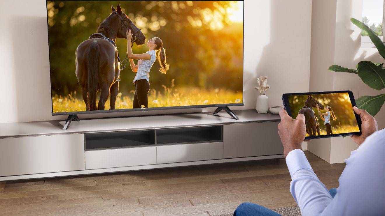 Személy tévét néz, a táblagépen ugyanaz a kép látható.