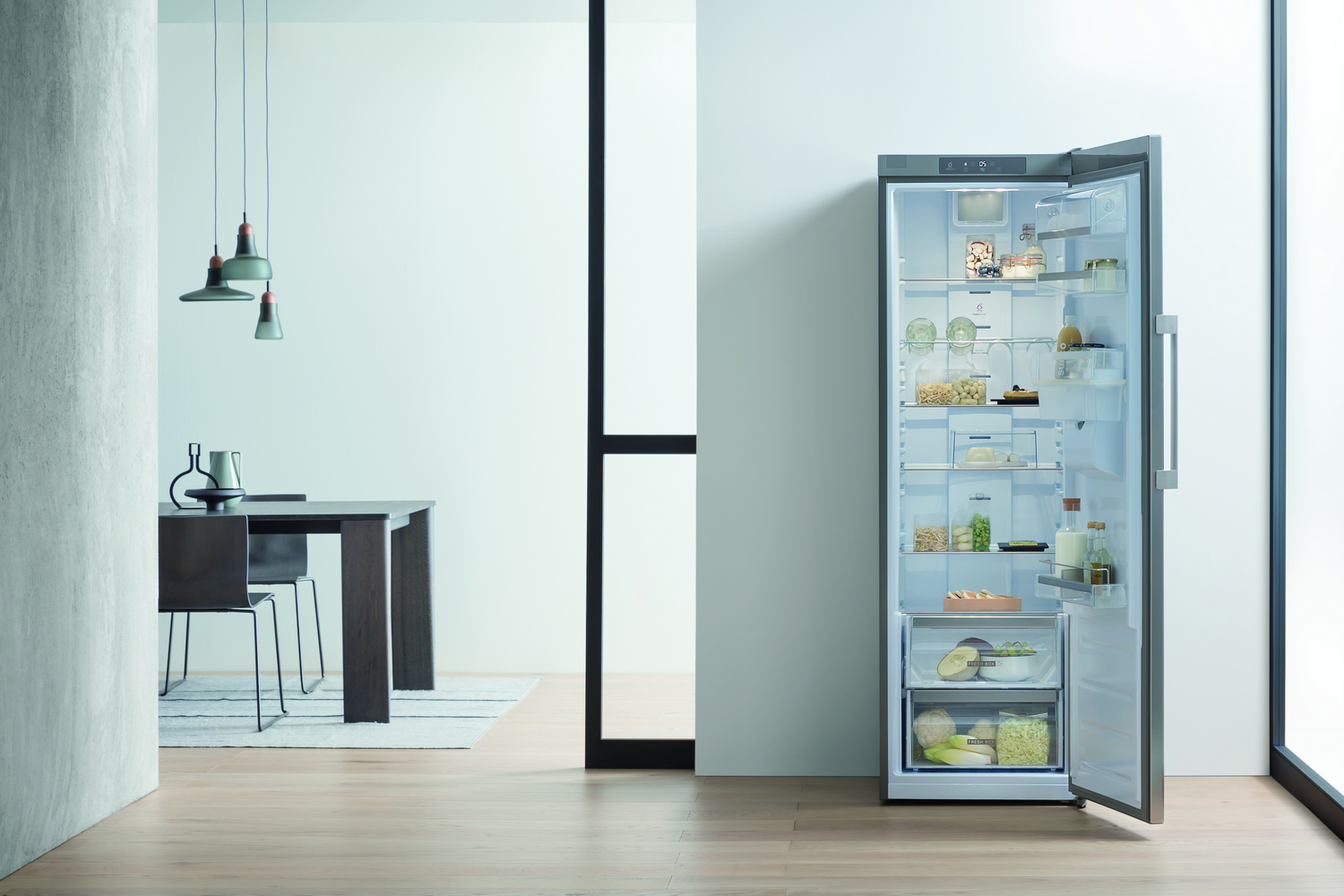 Refrigerador con puerta abierta. Dentro, estantes con alimentos, con un comedor al fondo.