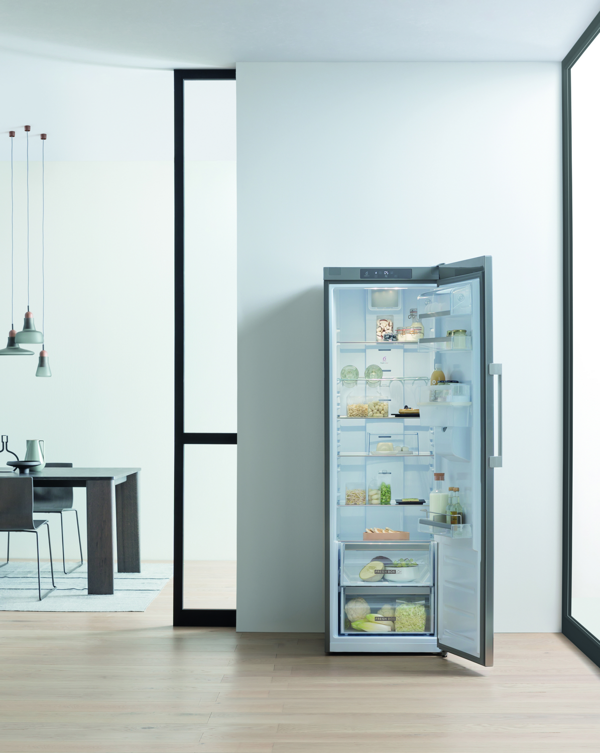 Un refrigerador con la puerta abierta, completamente lleno de comida, el fondo es blanco.